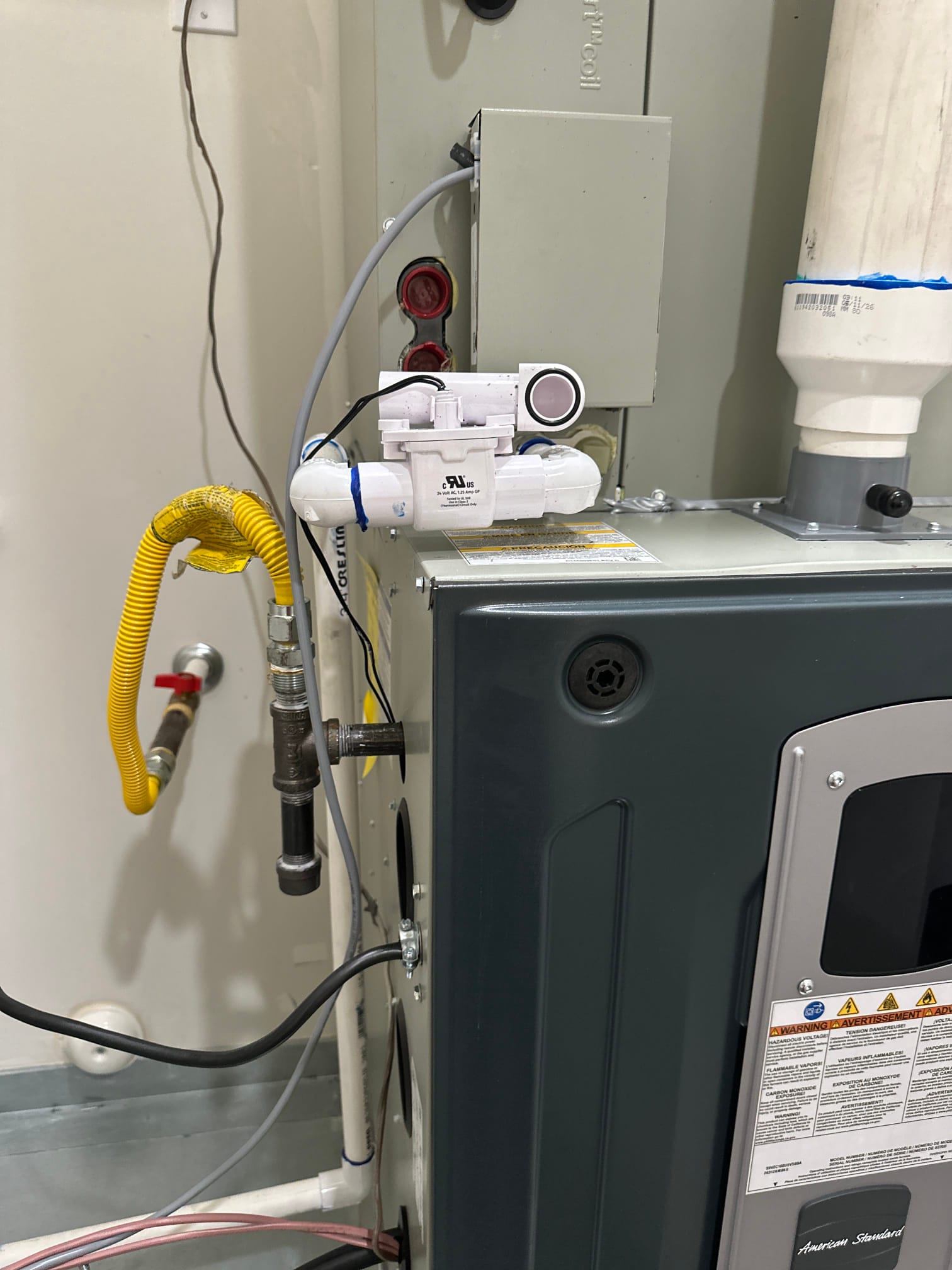 New high-efficiency furnace installed with condensate trap and sensor, gas flex connector, PVC venting, and electrical whip neatly routed.