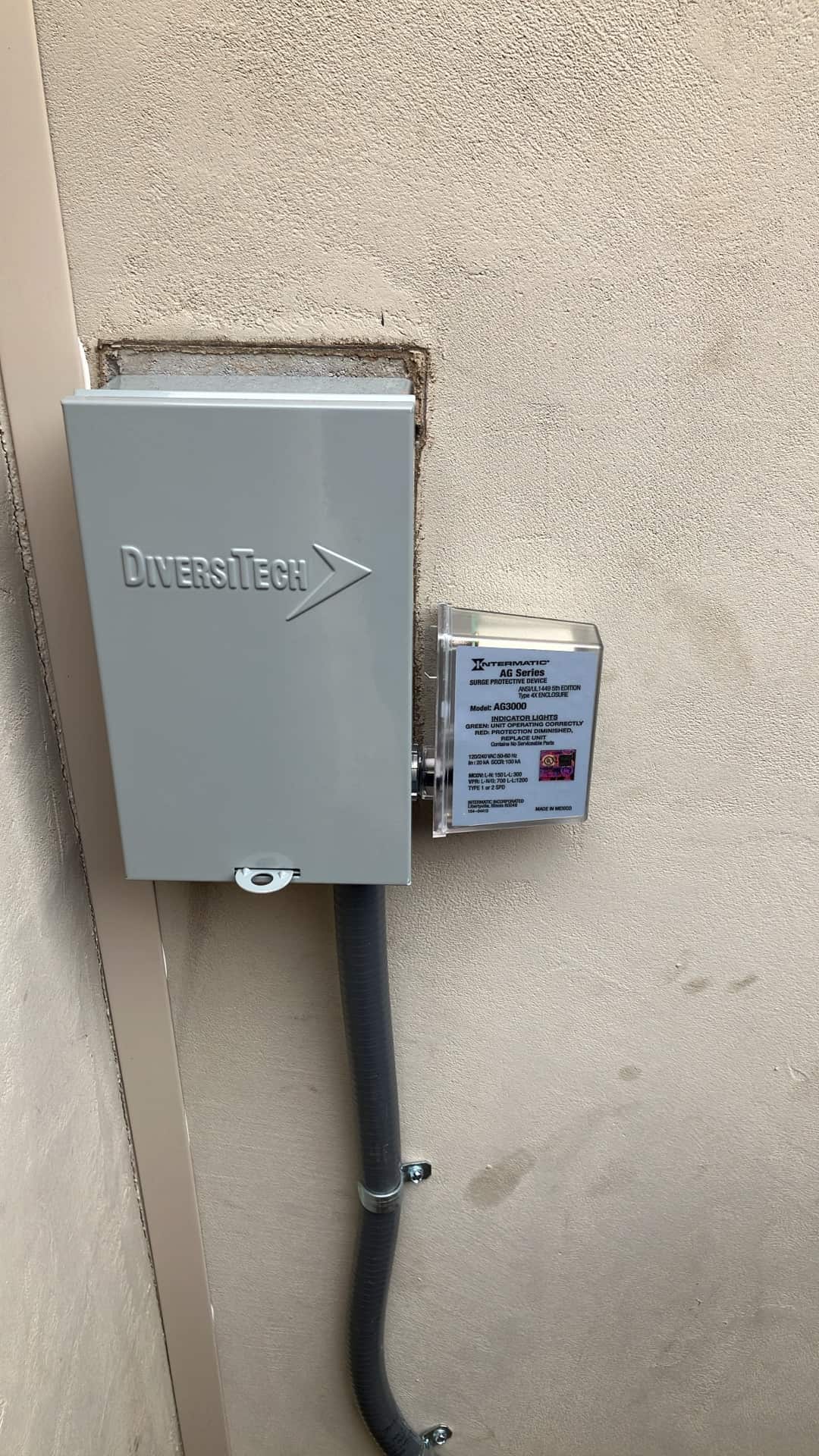 Outdoor HVAC disconnect with flexible conduit and a mounted surge protective device installed on the exterior wall.