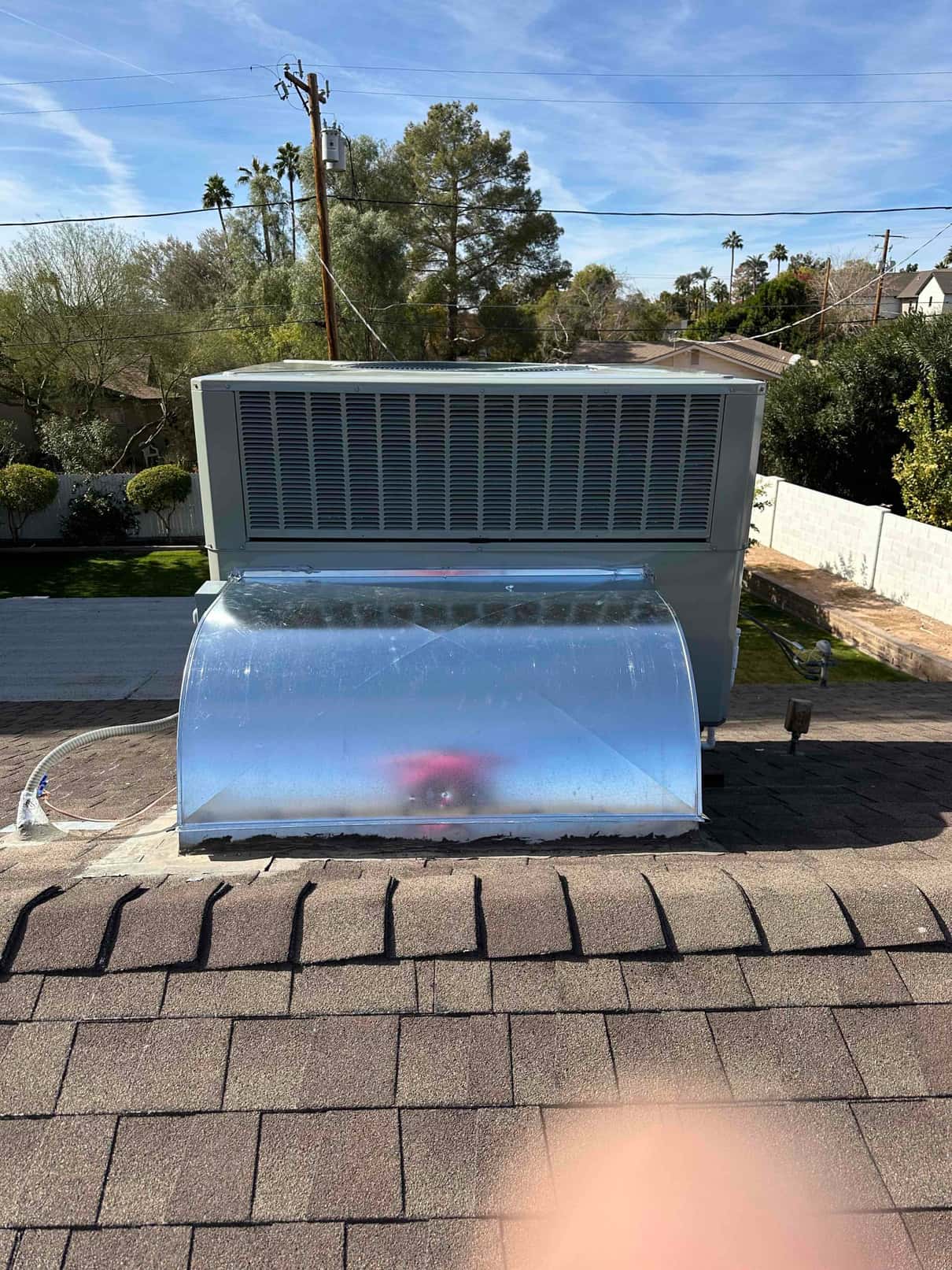 Rooftop package HVAC unit installed on shingles with new curb, sealed transitions, and insulated condensate drain routing.