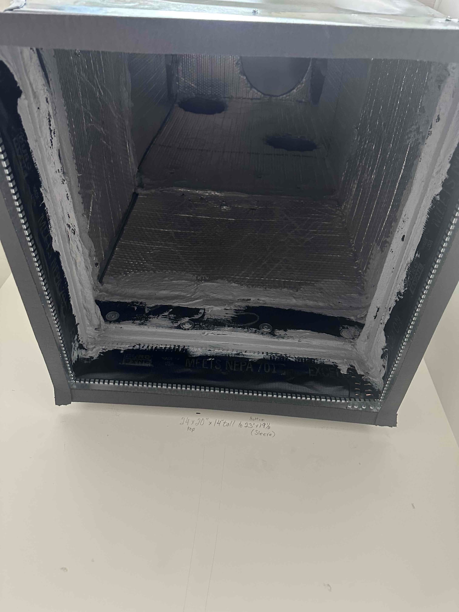 Sheet-metal duct transition with internal insulation and sealed seams, showing mastic and screws securing the new airflow connection.