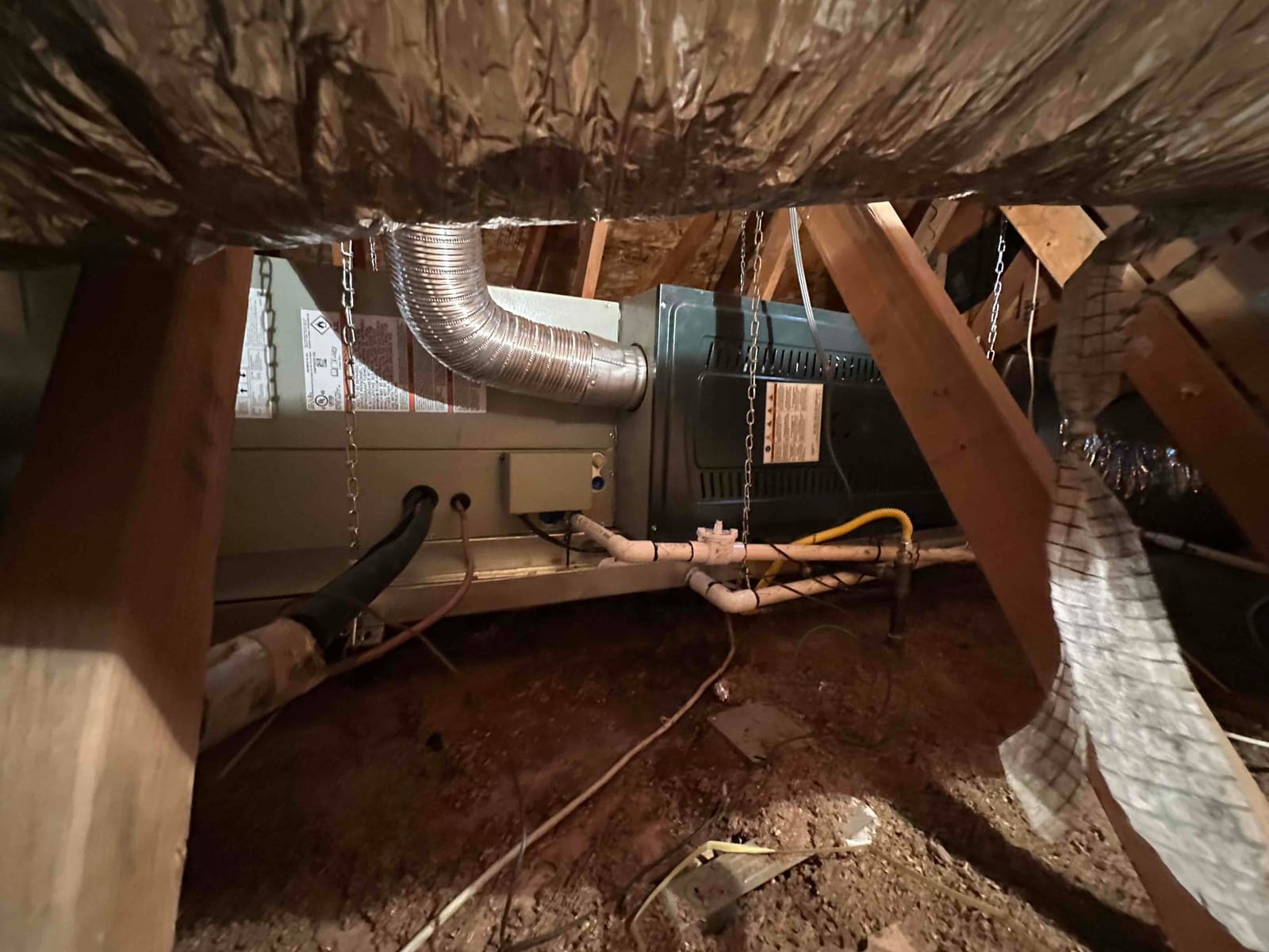 Air handler and furnace assembly hung in attic with insulated duct, condensate drain piping, gas line, and electrical whip routed.