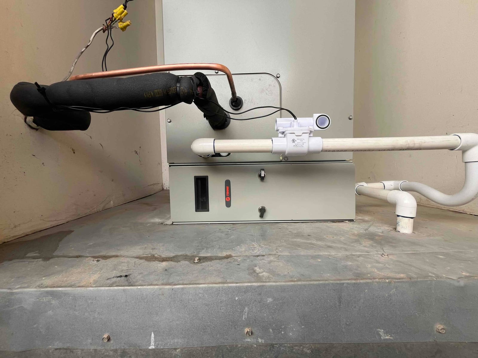 Air handler set on a platform with insulated refrigerant lines and newly plumbed condensate drain featuring a float safety switch.