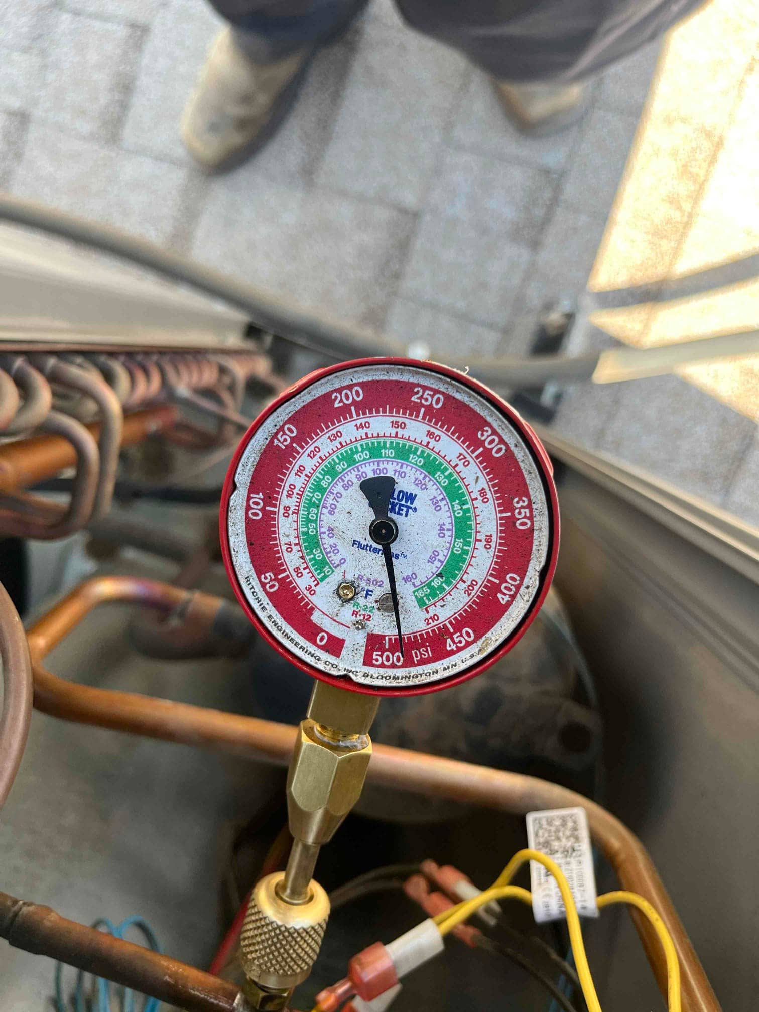 Analog manifold gauge connected to the low-side service port shows 98 psi during air conditioning diagnostic testing.