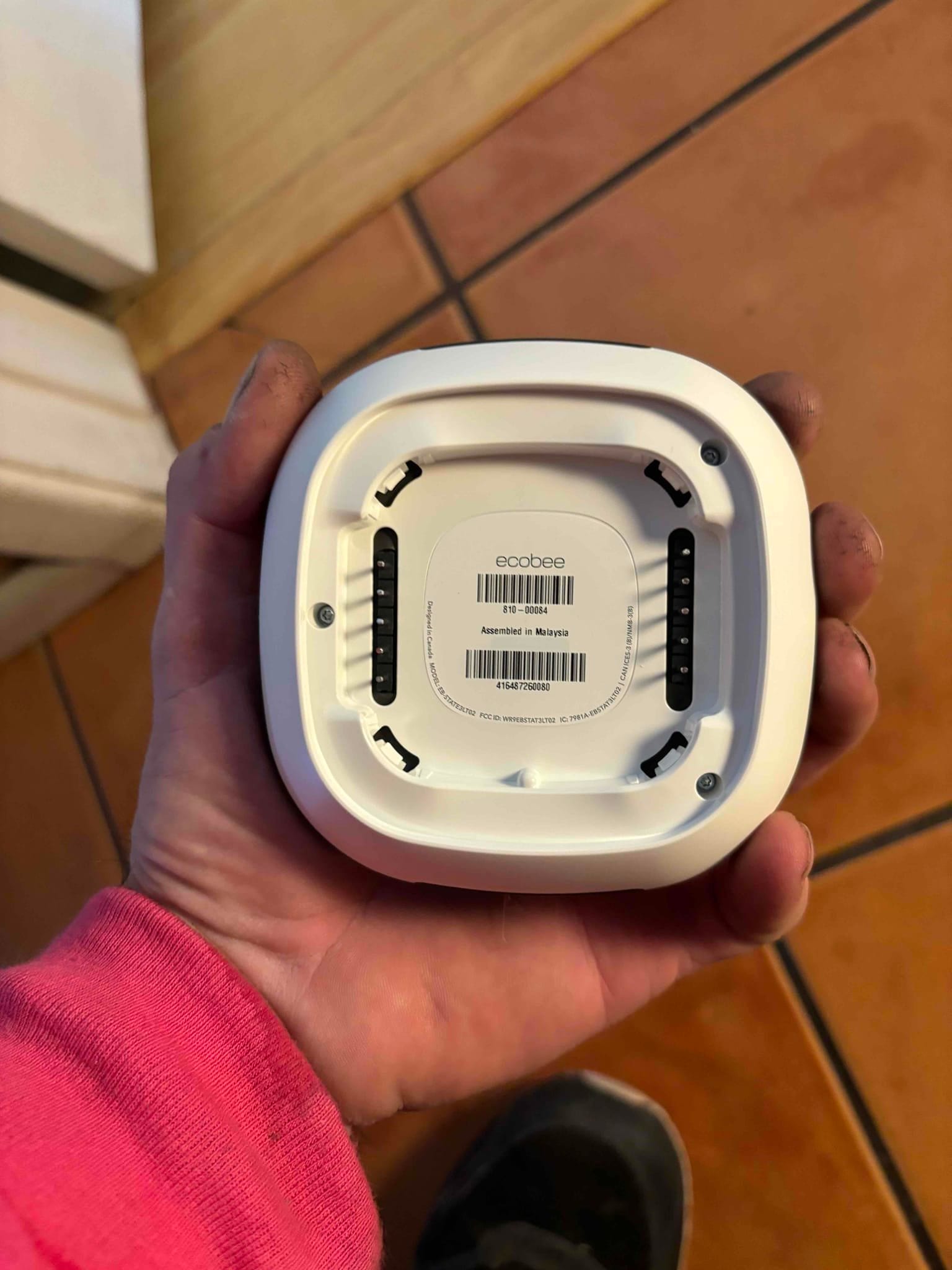 Back of a smart thermostat head unit shown before mounting onto the wall plate during installation.