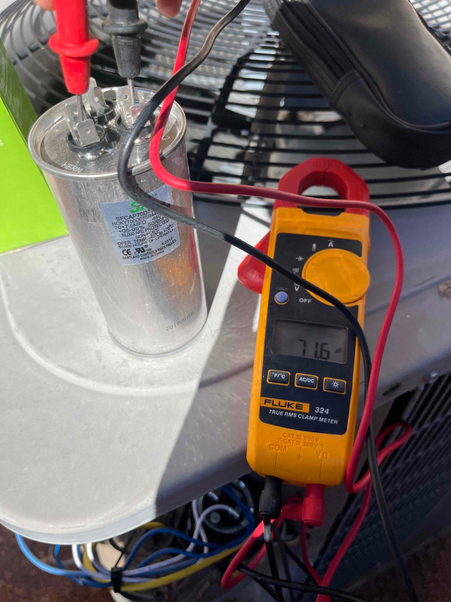 Clamp meter in capacitance mode reads 16.0 μF while testing the dual-run capacitor terminals on the outdoor condenser.