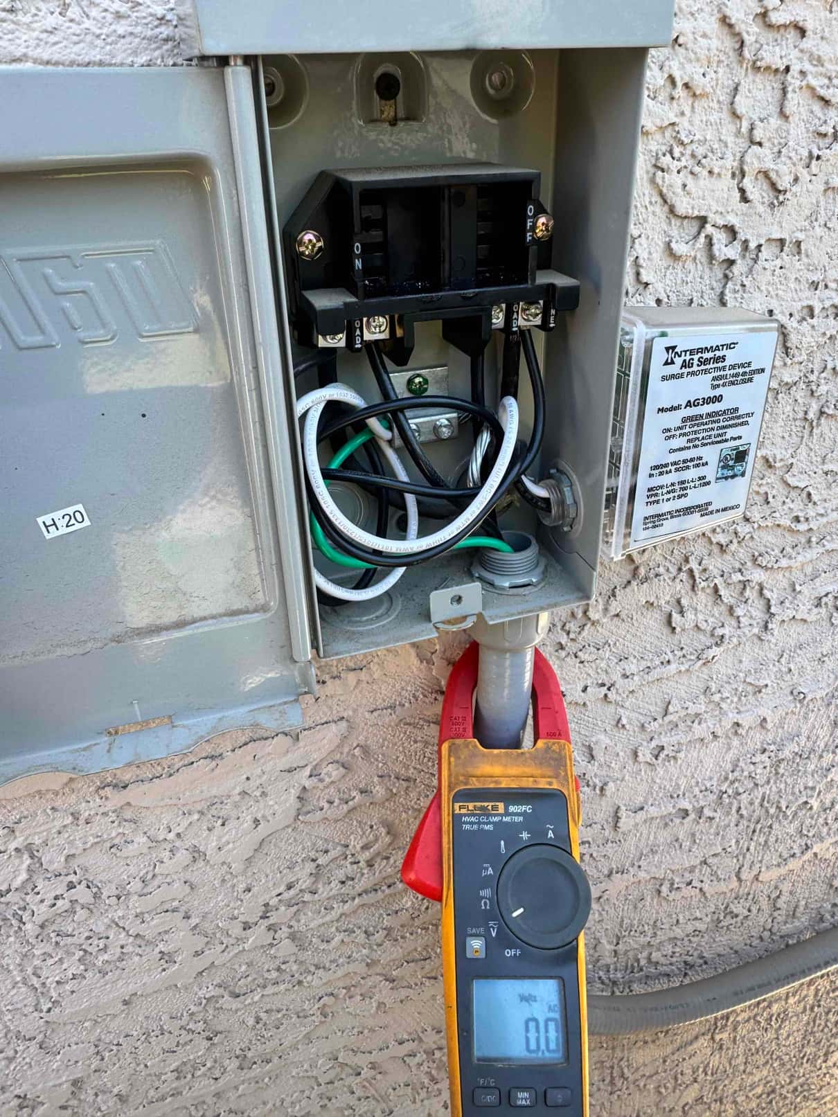 Clamp meter shows 0.0 A on a conductor at the fused disconnect with wiring exposed for testing.
