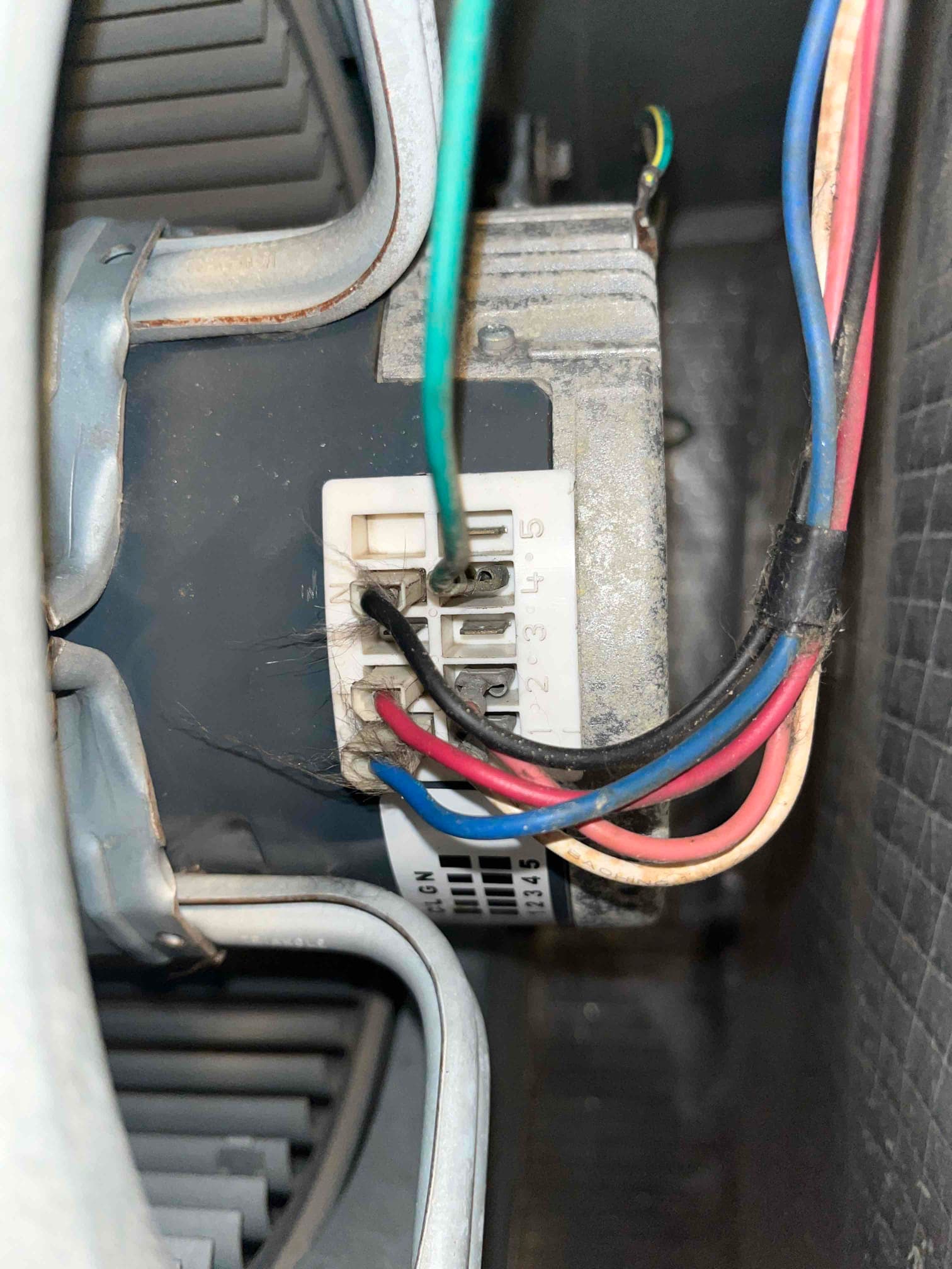 Close-up of an ECM blower motor connector with multiple colored wires attached to labeled terminals inside the air handler.
