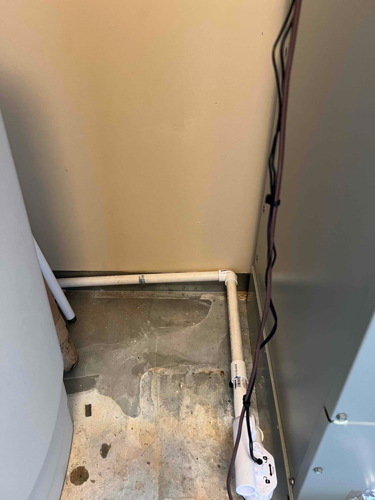 Condensate drain piping installed beside the air handler with a cleanout and safety float switch on the trap assembly.