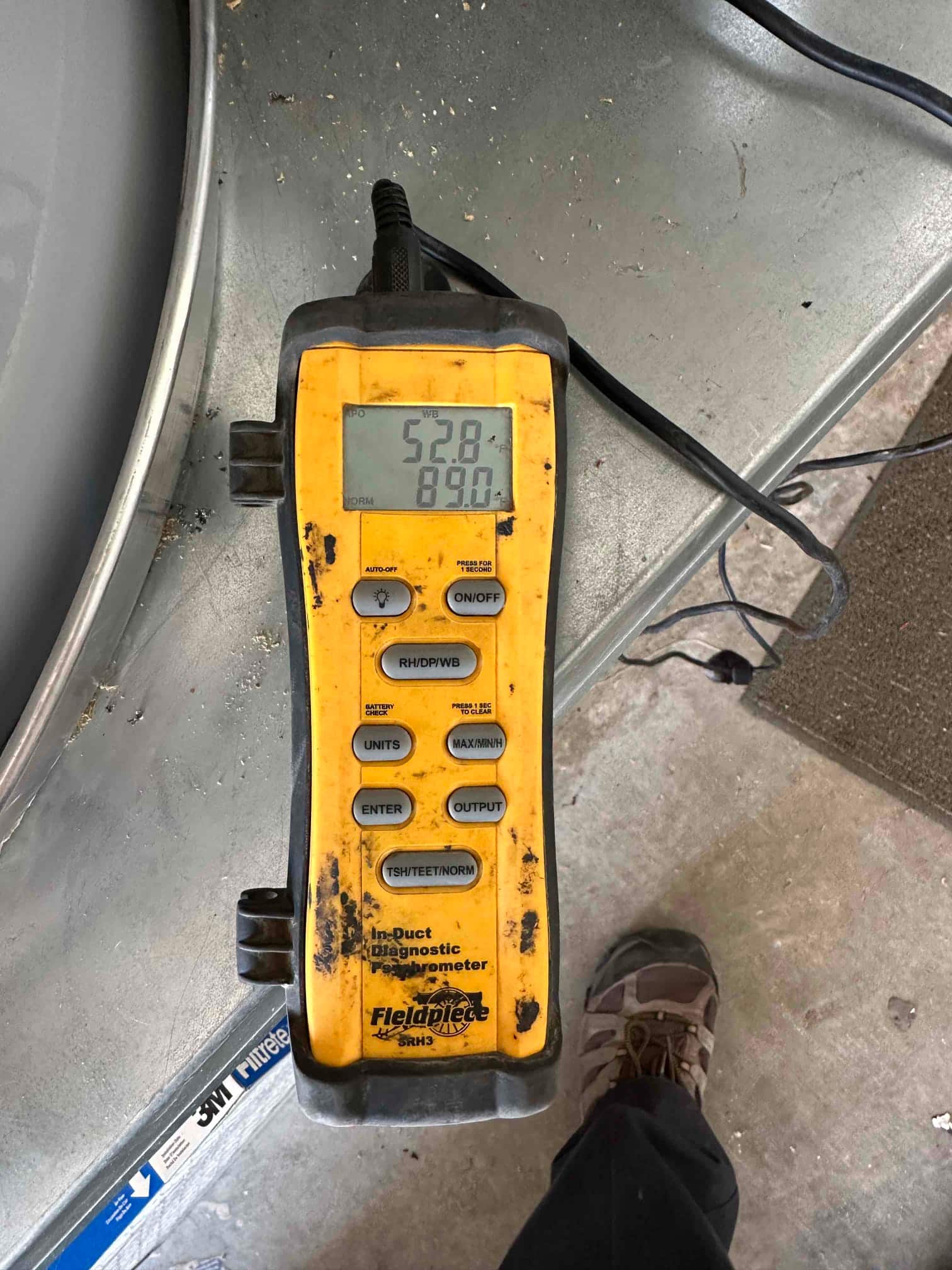 Digital in-duct thermometer displays 52.8 degrees, documenting cooled supply air temperature during system commissioning.