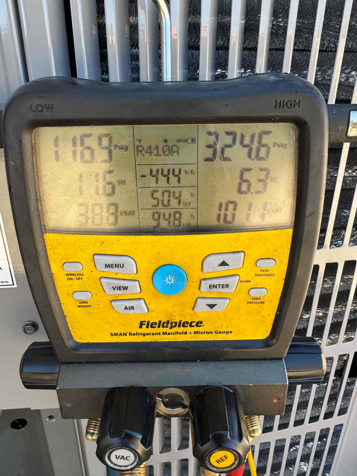 Digital manifold connected at the outdoor unit shows operating pressures and temperatures during system commissioning.