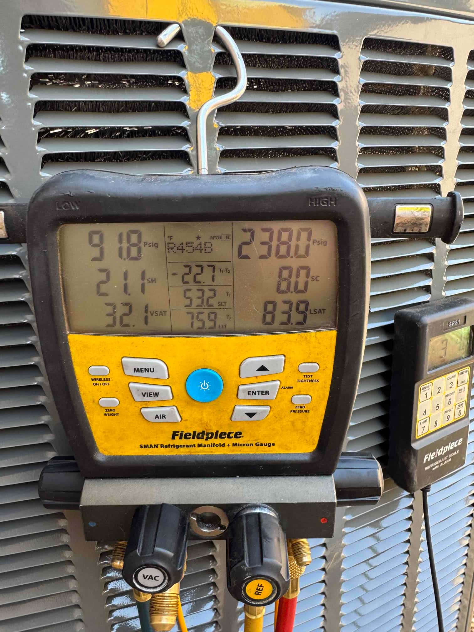 Digital manifold on the outdoor condenser shows operating pressures with R-454B selected during system commissioning.