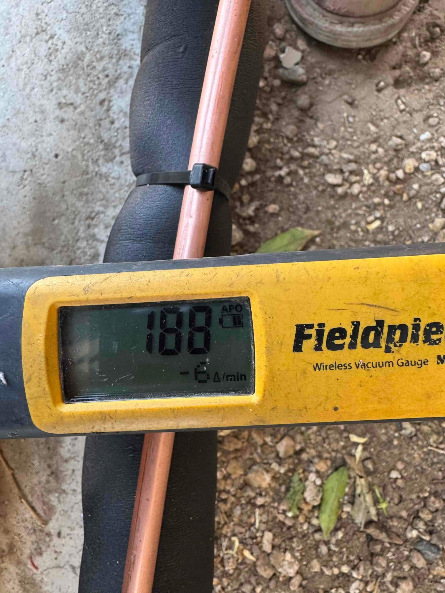 Digital micron gauge on the refrigerant line shows 188 microns during evacuation, confirming a deep vacuum before charging.