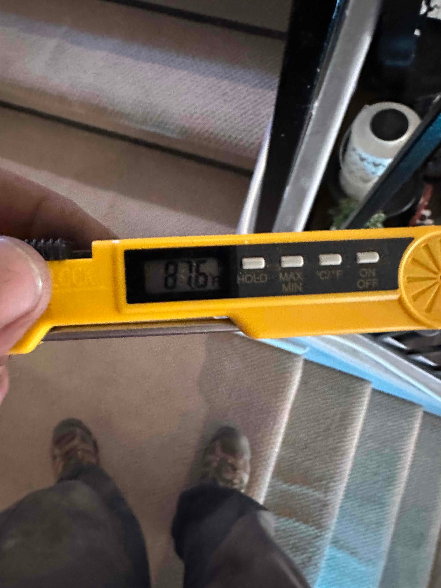 Digital thermometer displays 87.6 degrees Fahrenheit while checking air temperature during system commissioning.