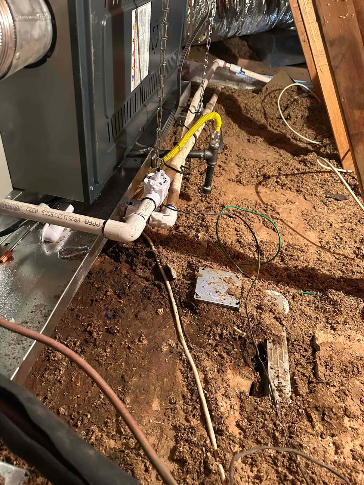 Horizontal furnace and coil on a drain pan with PVC condensate piping, gas flex connector, and suspended support chains in attic.