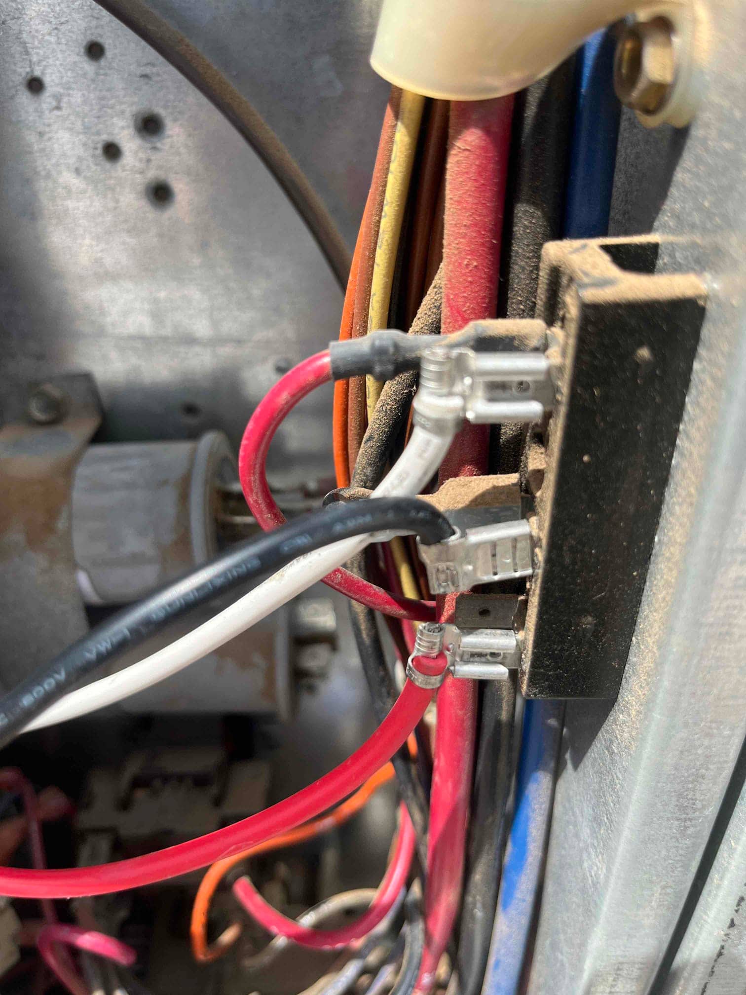 Indoor air handler wiring connections with spade terminals and color-coded conductors, showing dust accumulation near the blower compartment.