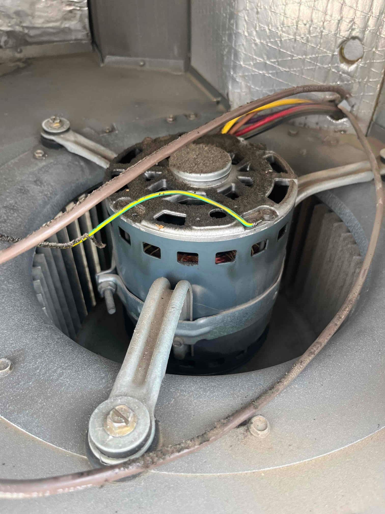 Indoor blower motor inside the air handler housing, showing dust accumulation on the motor and wiring.