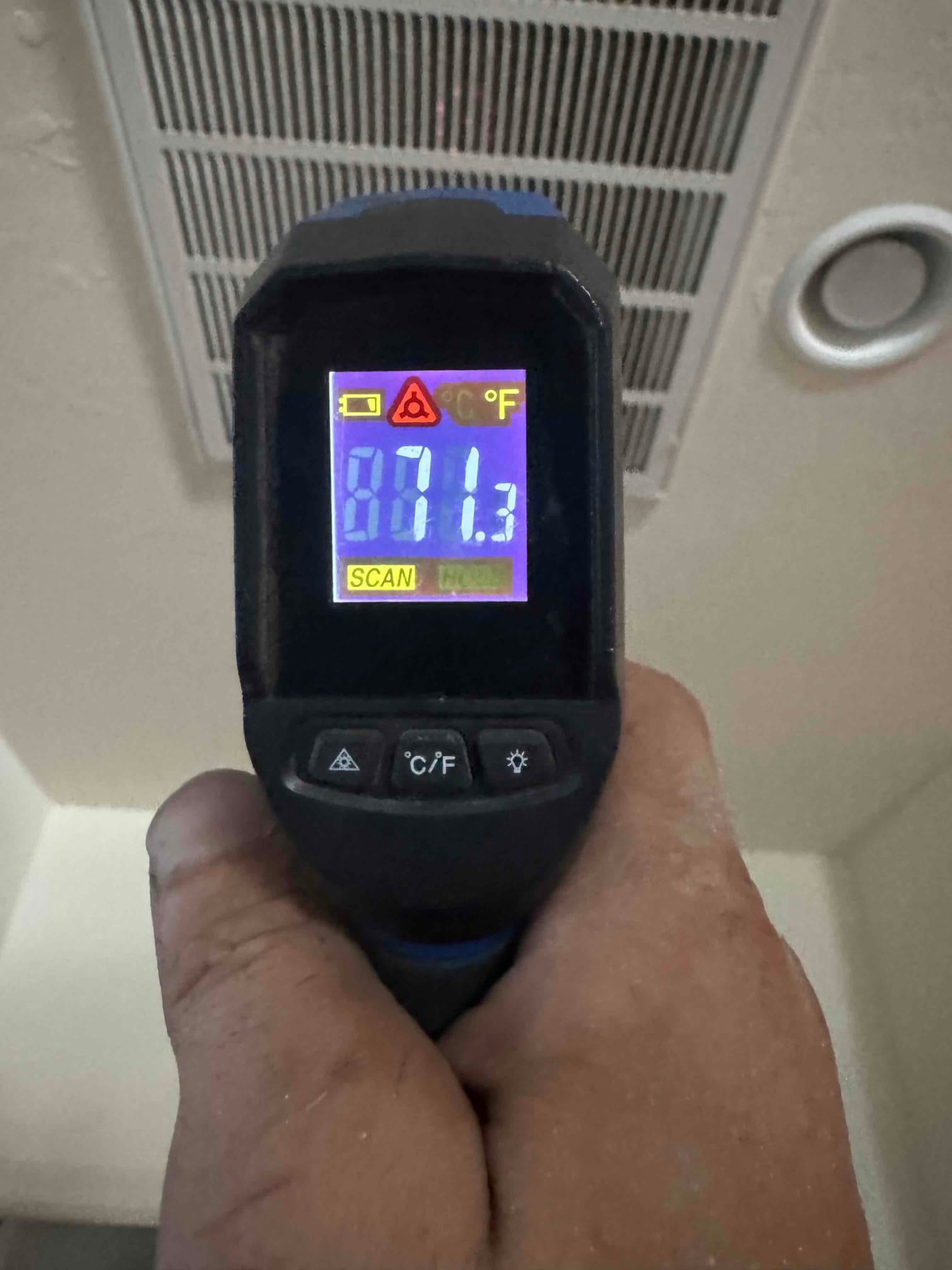 Infrared thermometer reads 81.3°F while aimed at a return air grille during air temperature check.