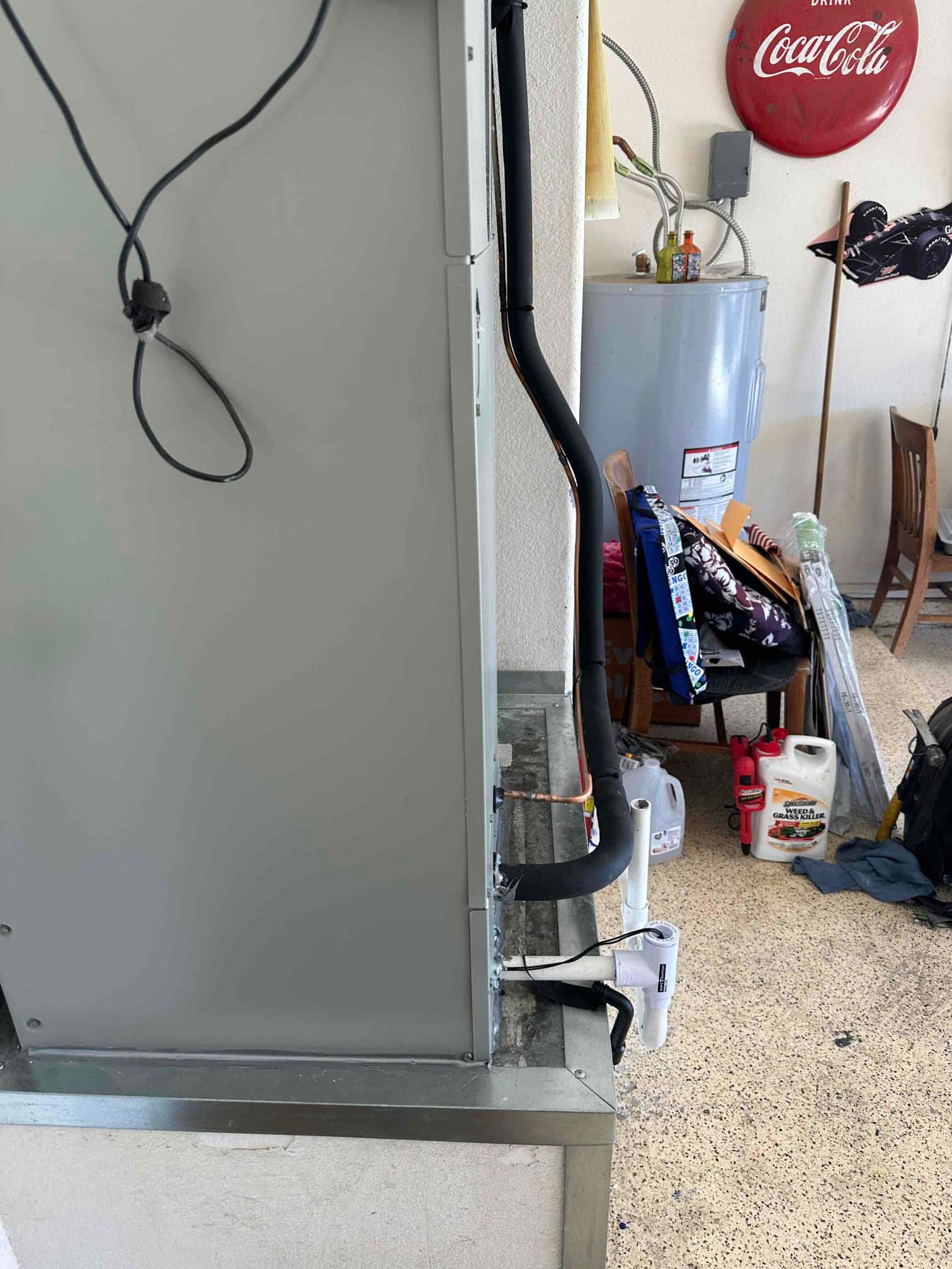 New air handler set on a platform with insulated refrigerant lines and condensate drain assembly installed and routed to PVC.