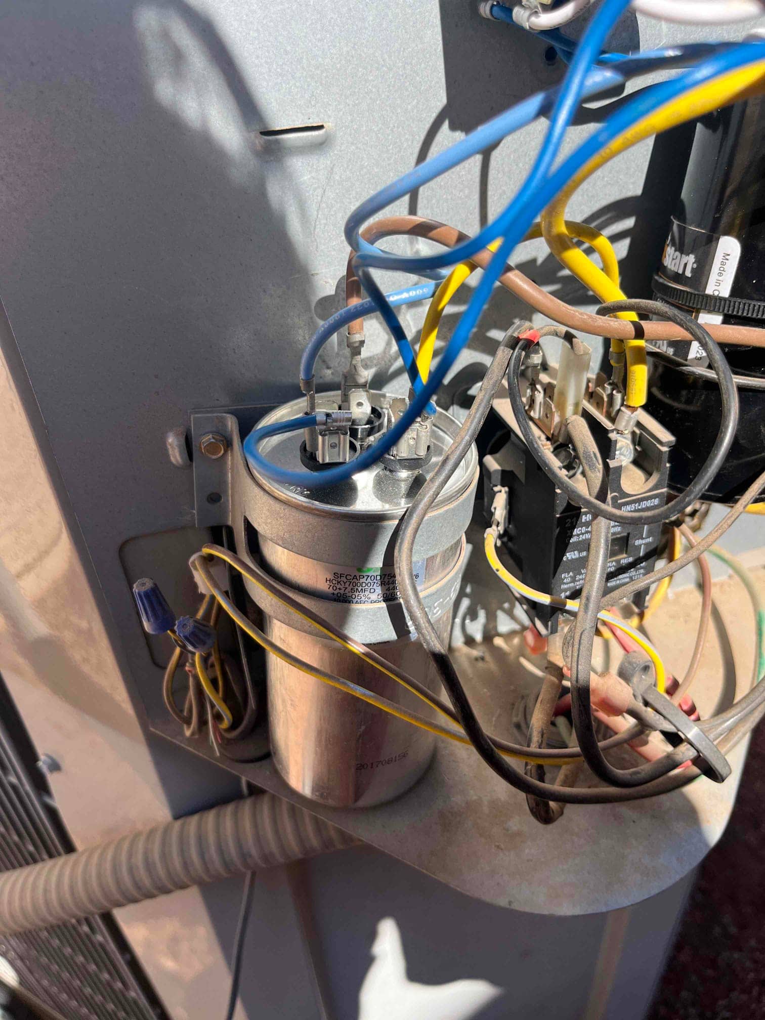 New dual run capacitor installed in the condenser, with connected brown, yellow, and blue wires routed to contactor and motor.