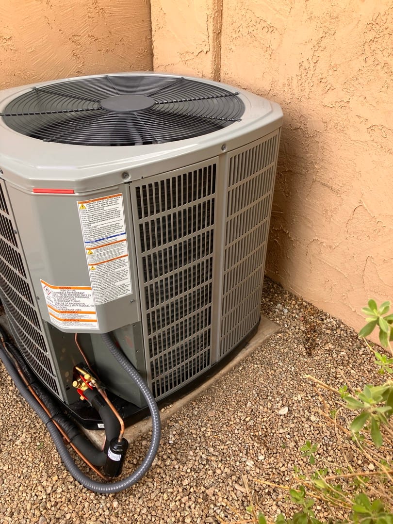 New outdoor condenser set on a level pad with connected refrigerant lines, insulated suction line, and flexible electrical whip.