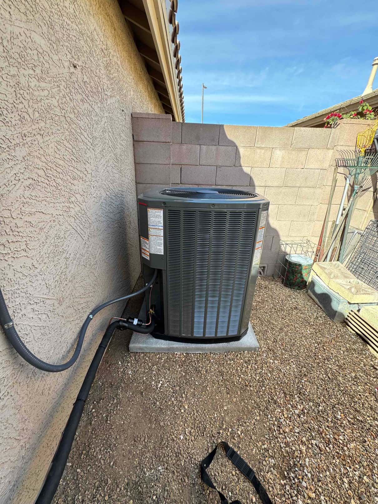 New outdoor condenser set on a level pad with insulated refrigerant lines routed along the exterior wall.