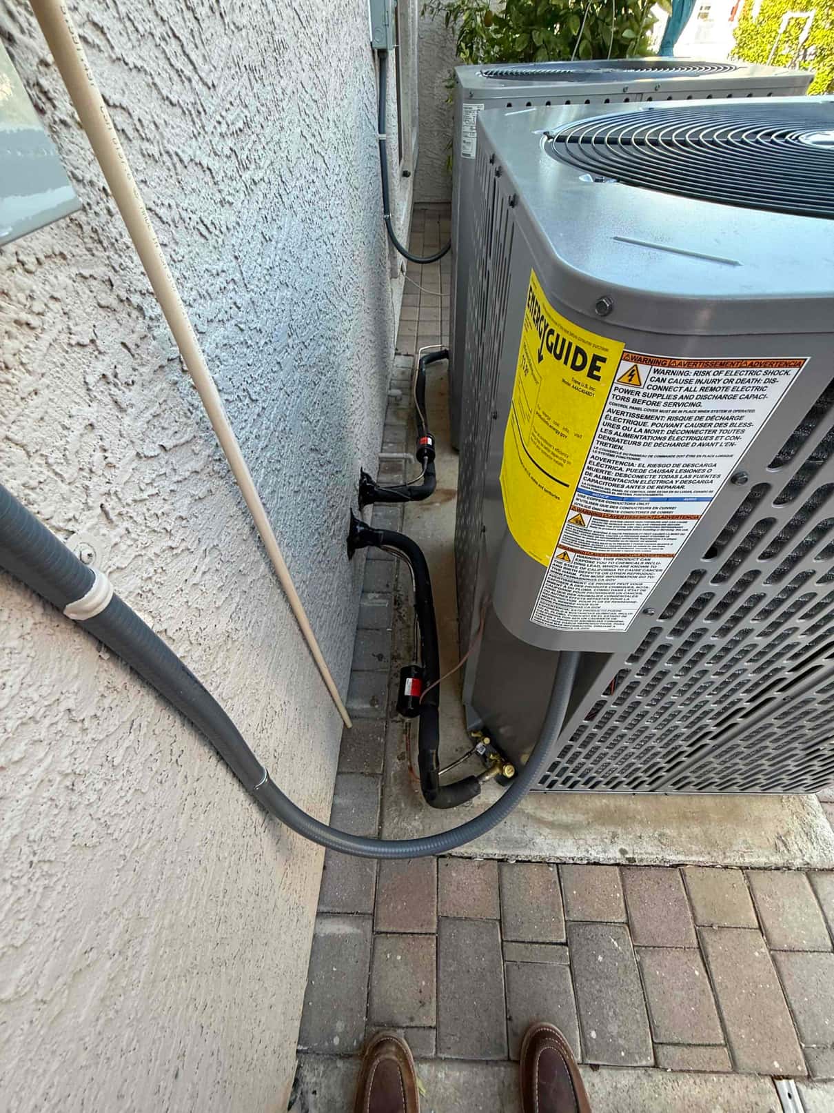 Two new outdoor condensers installed on pads with insulated refrigerant lines, electrical whip, and sealed wall penetrations along the side yard.