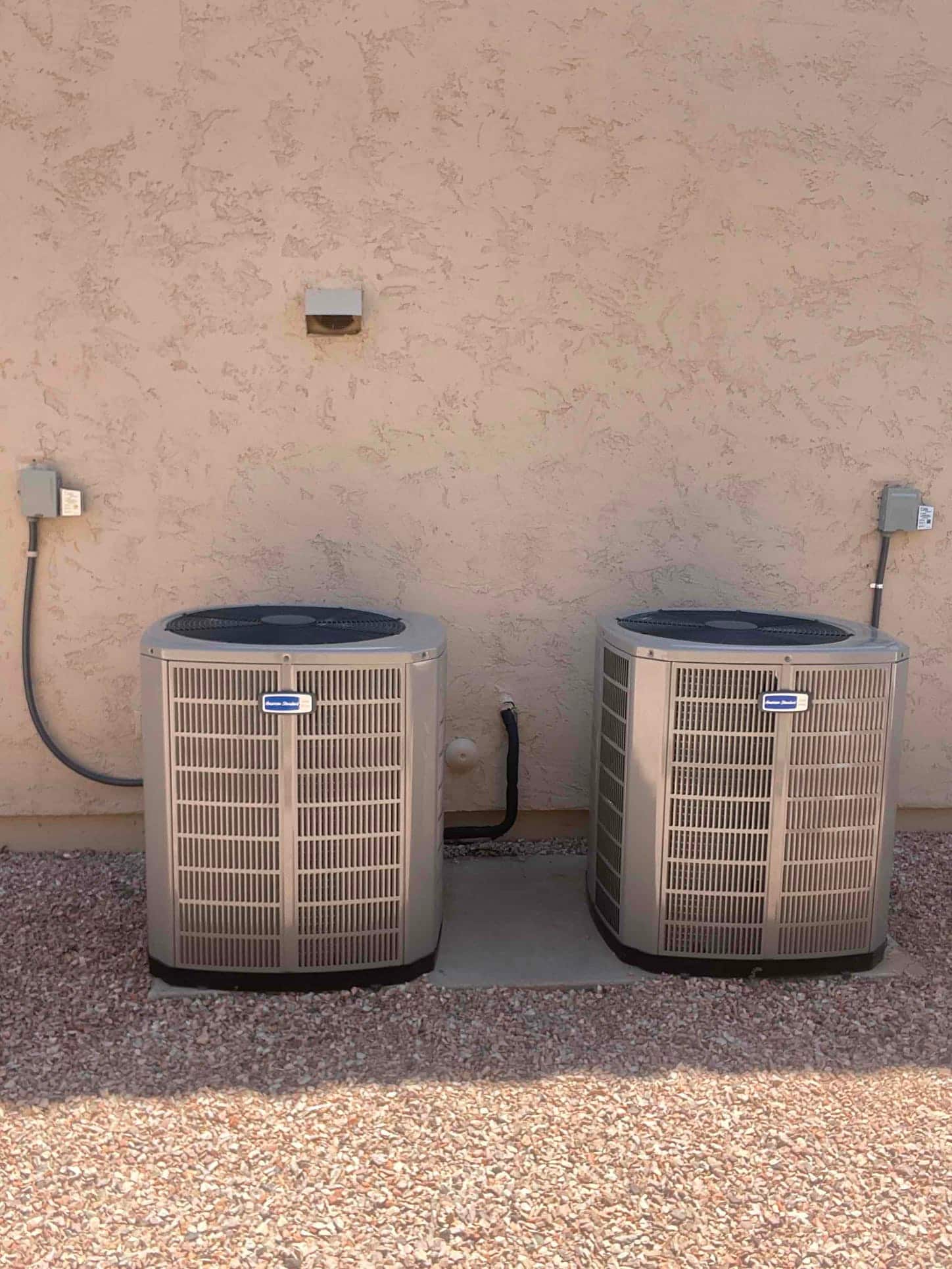 Two new outdoor condensers set on a level pad with insulated line set and electrical disconnects mounted nearby.