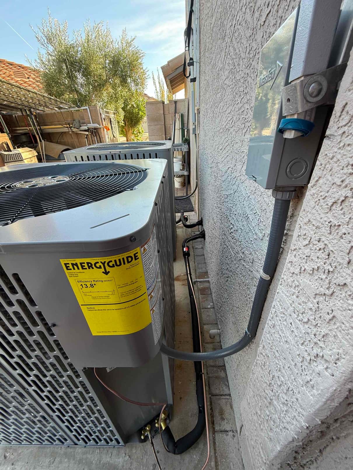 New outdoor condensers set on pads with insulated refrigerant lines, sealed wall penetrations, and a mounted weatherproof electrical disconnect.