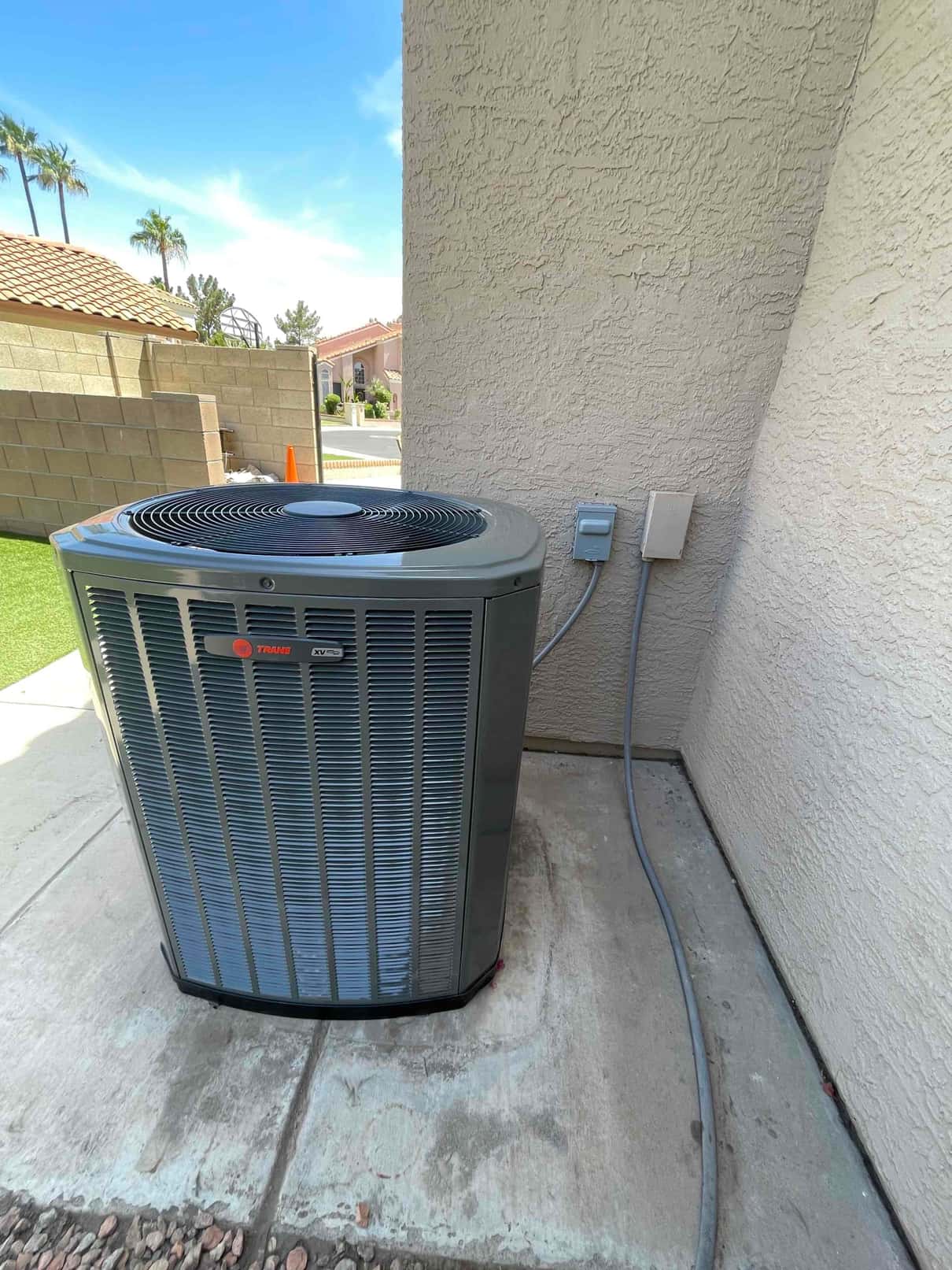 New outdoor heat pump condenser set on a concrete pad with weatherproof disconnect and sealed line set penetration.