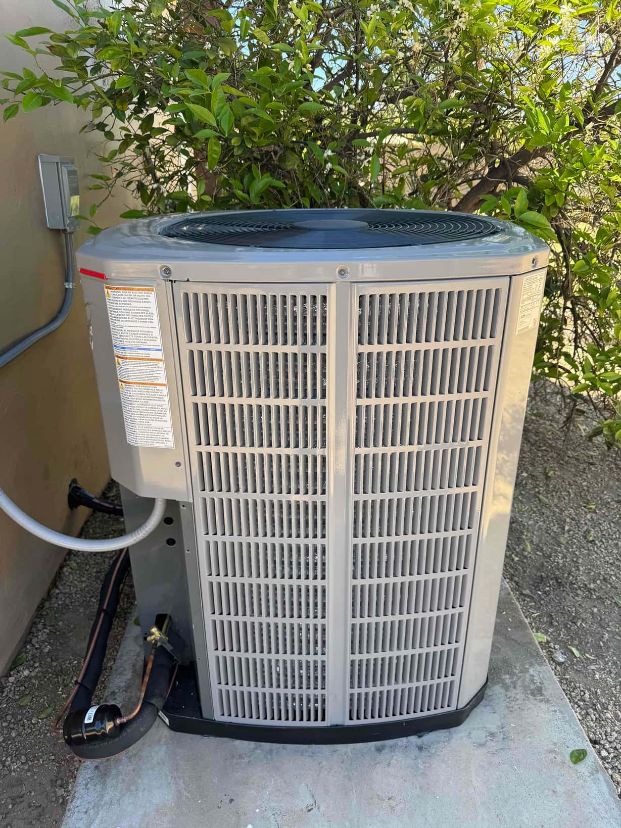 New outdoor heat pump condenser set on a level pad with insulated line set and exterior disconnect installed.