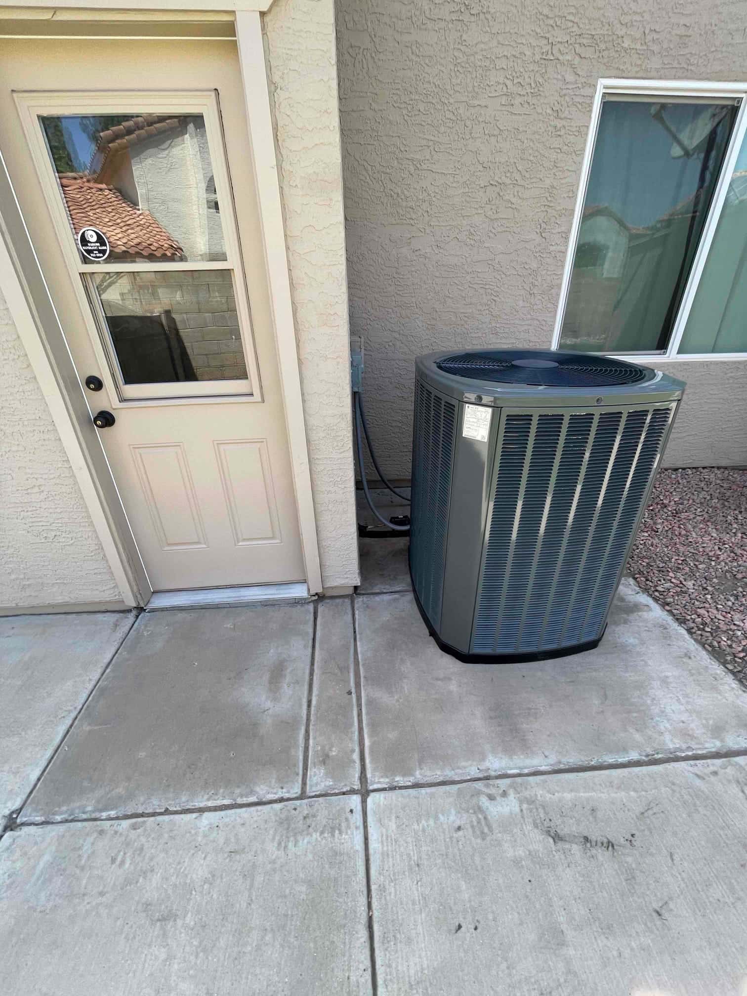 New outdoor heat pump condenser set on a level pad with insulated line set and exterior disconnect adjacent to the unit.