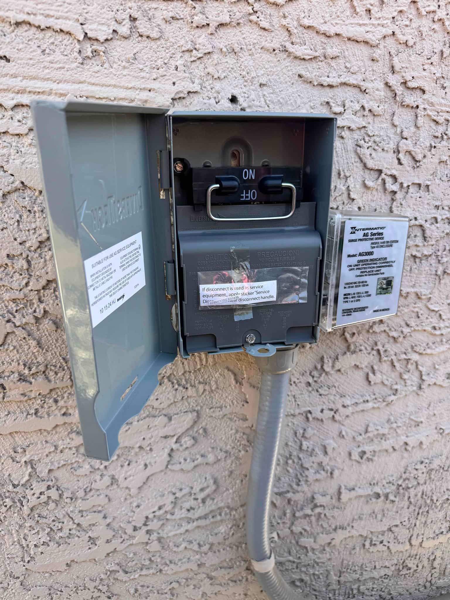 Outdoor air conditioner disconnect with pull-out fused handle in the ON position inside the weatherproof enclosure, showing installed wiring conduit.