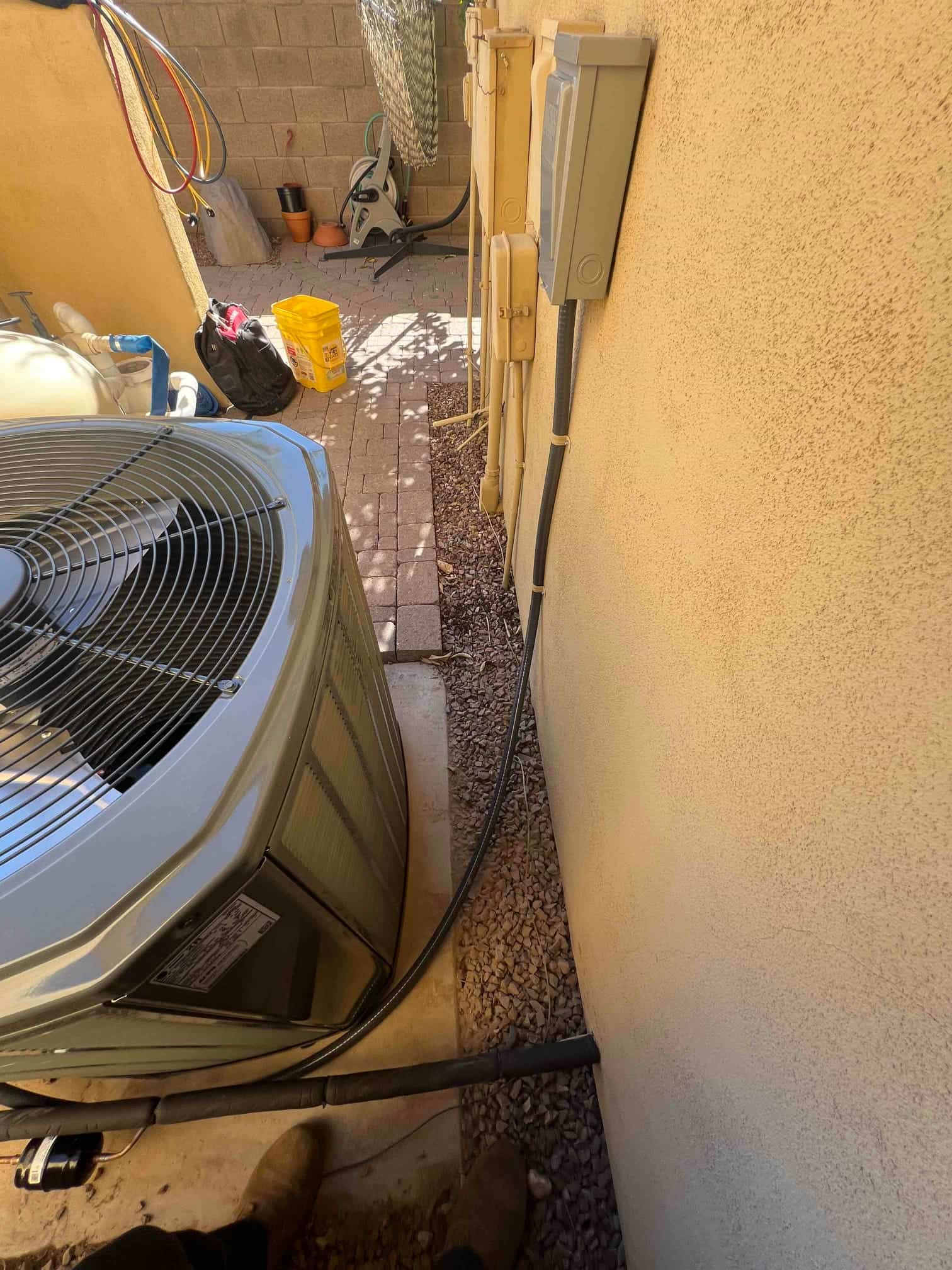Outdoor condenser set on a level pad with new electrical disconnect and sealed line set penetration along the exterior wall.