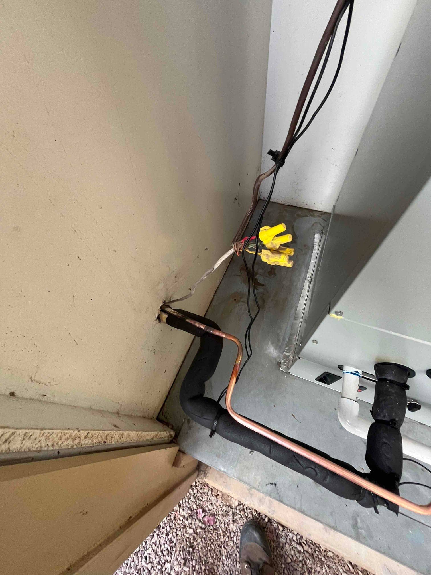 Refrigerant line set with insulation routed through wall to new air handler, alongside low-voltage wiring and condensate drain connection.