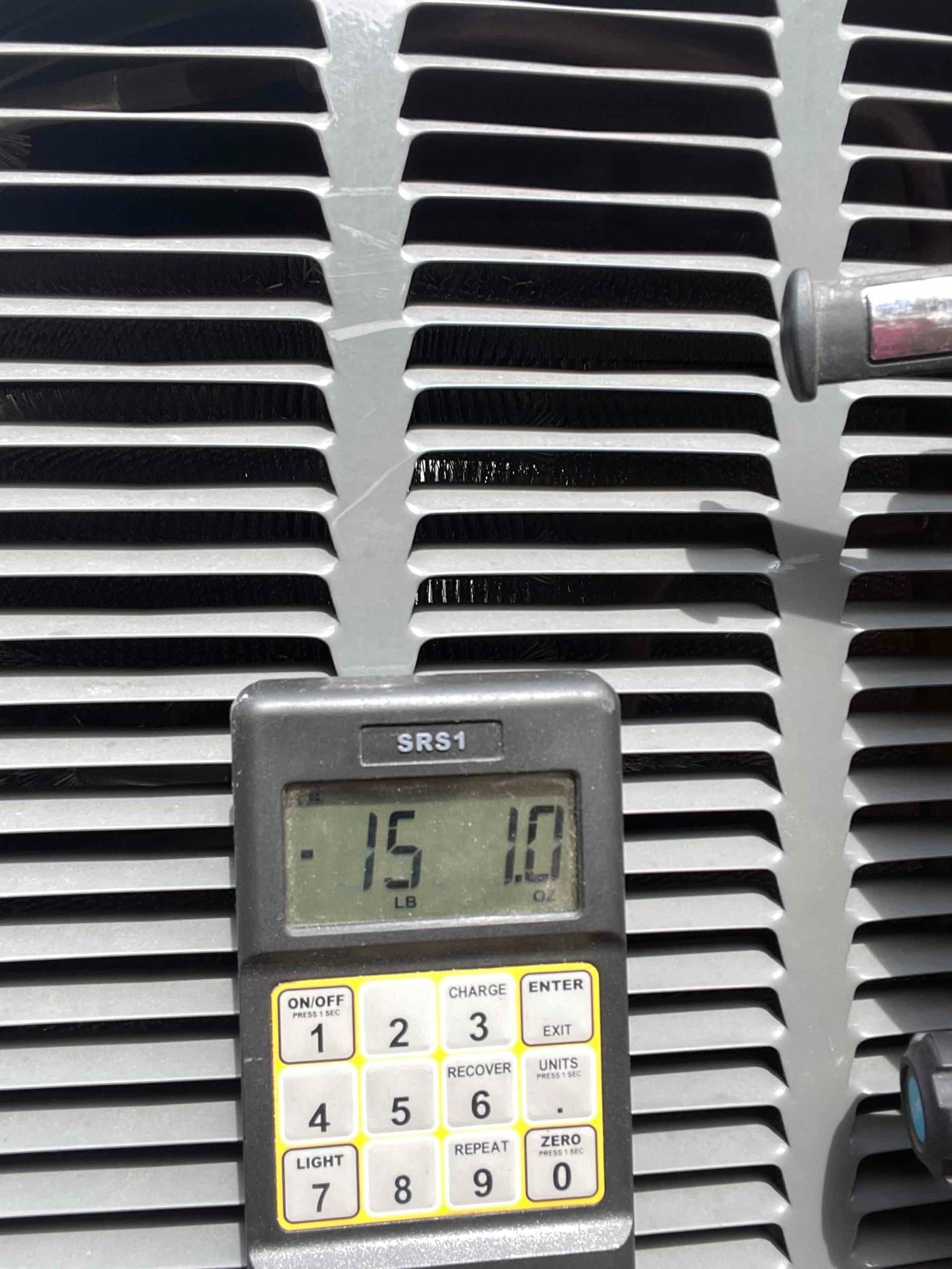 Refrigerant recovery scale in front of the condenser shows -1.5 lb on the digital display during service.