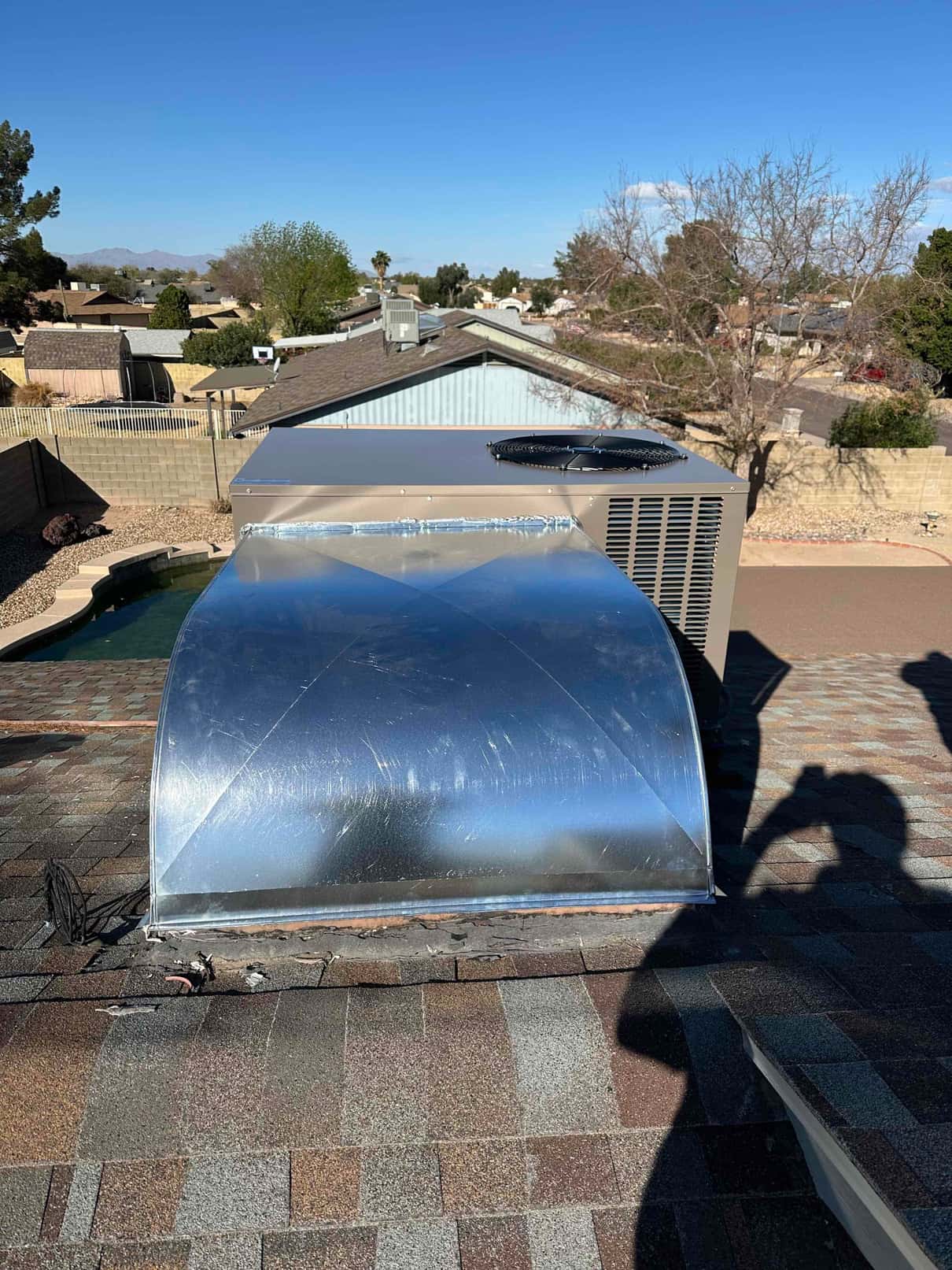 Rooftop package unit installed with new sealed supply plenum and curb on shingle roof, showing completed exterior duct connection.
