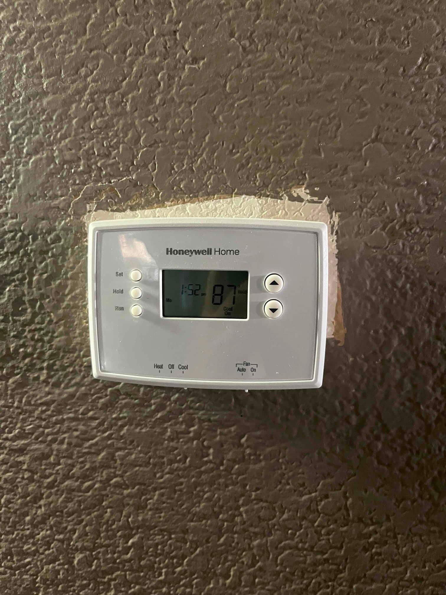 Wall-mounted thermostat displays a room temperature of 87°F, with setpoint and hold buttons visible below the screen.