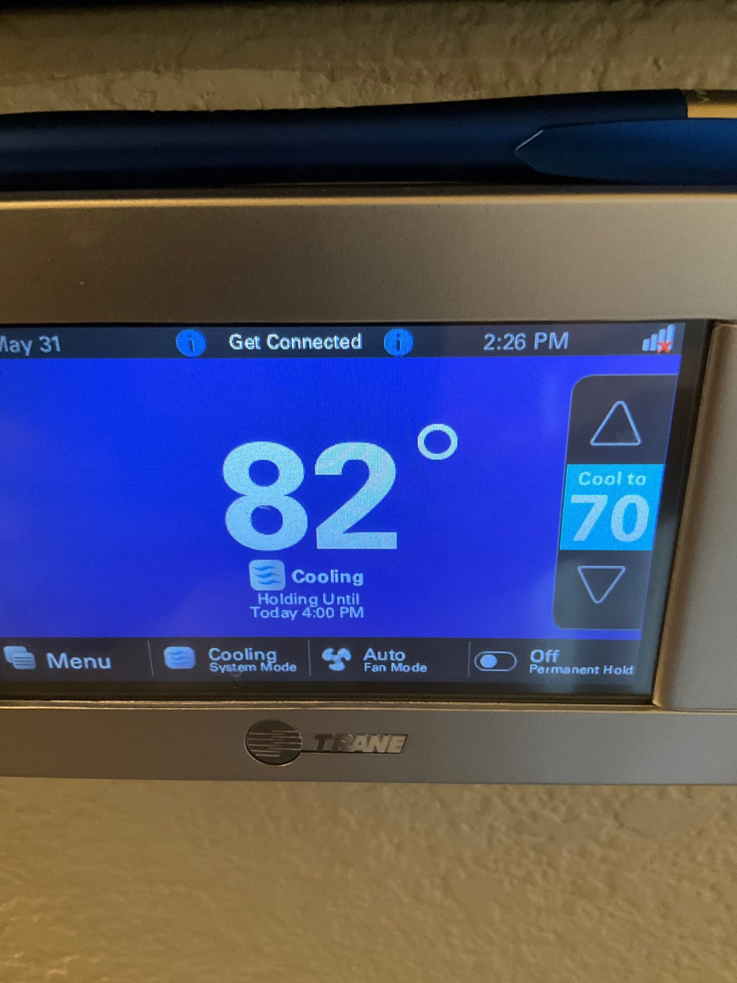 Wall-mounted touchscreen thermostat displays indoor temperature at 82 degrees with cooling mode active and setpoint at 70.