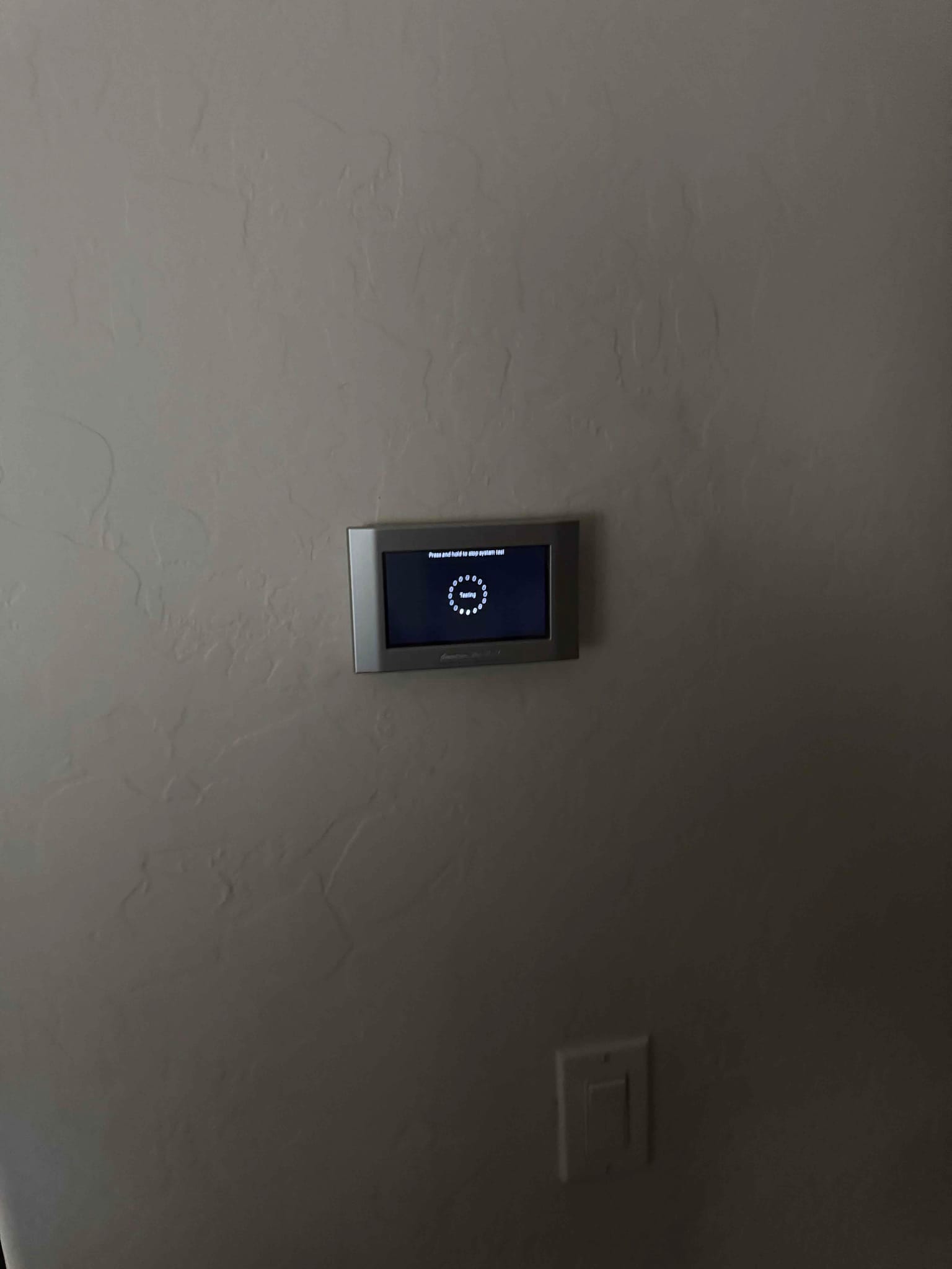 Wall-mounted touchscreen thermostat powering up on a newly installed HVAC system inside the home.