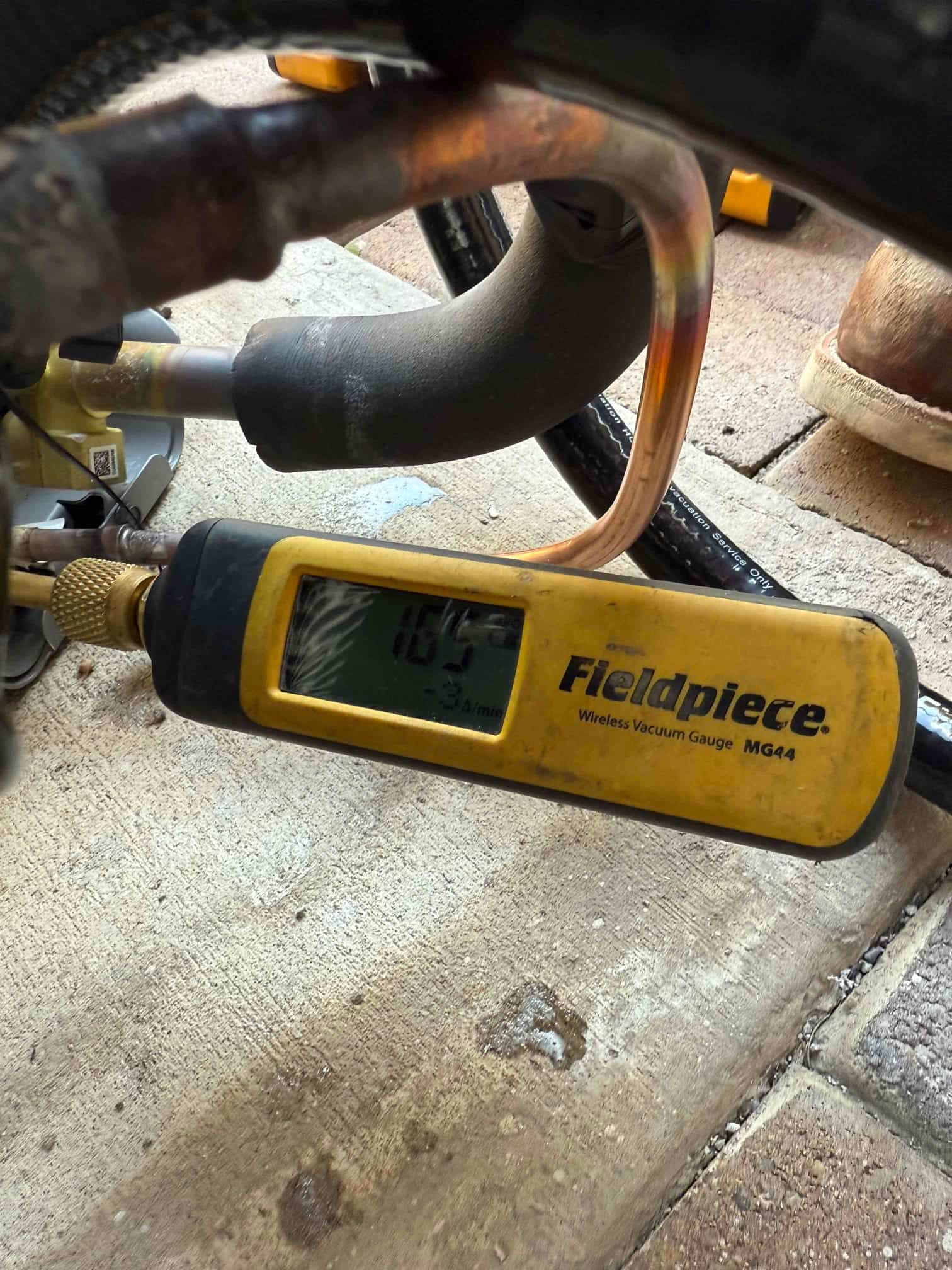 Wireless micron gauge connected to the system shows a deep vacuum achieved during evacuation before refrigerant charging.