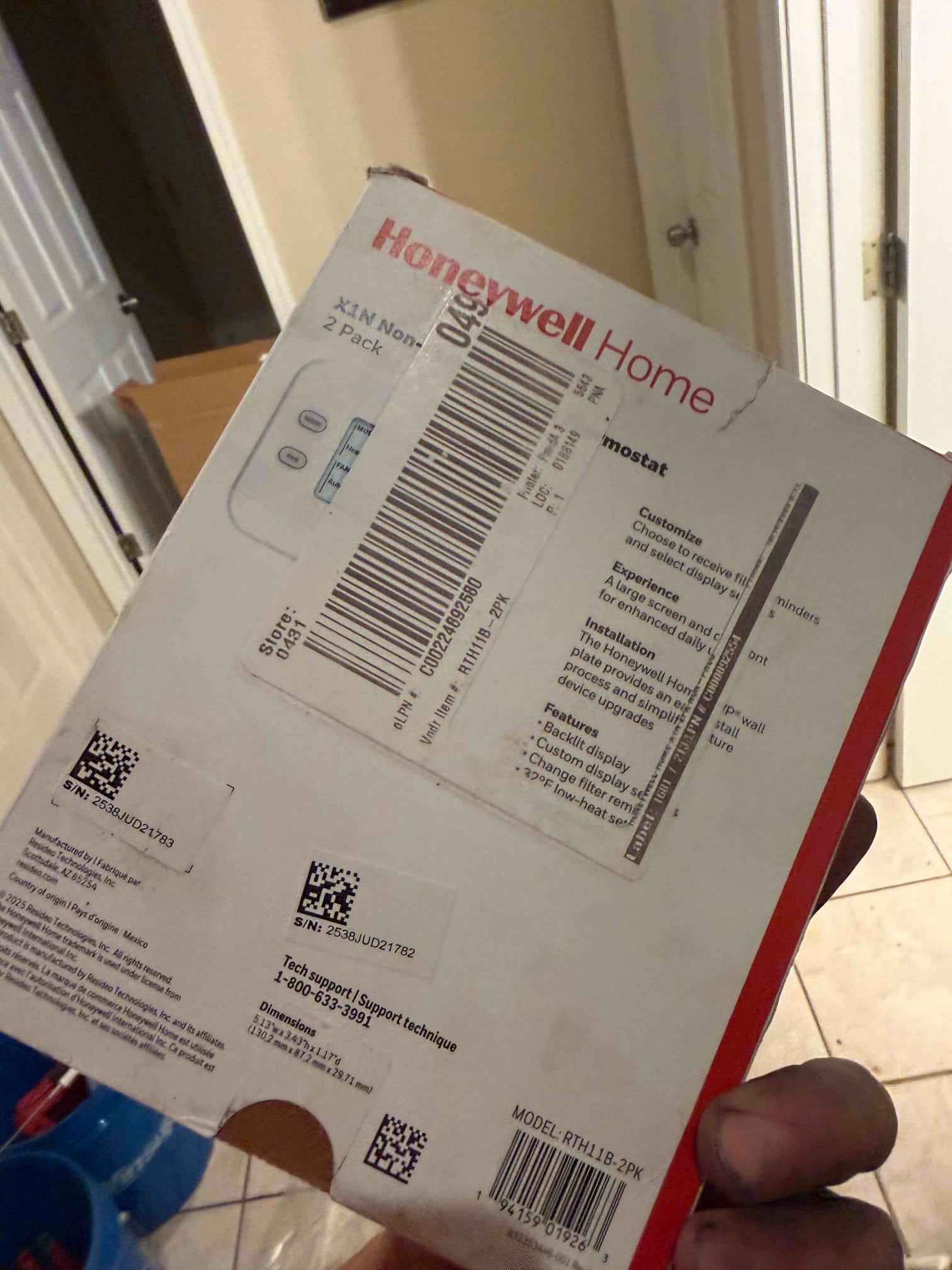 Box for a non-programmable thermostat held on site during an HVAC installation, showing packaging and product information.