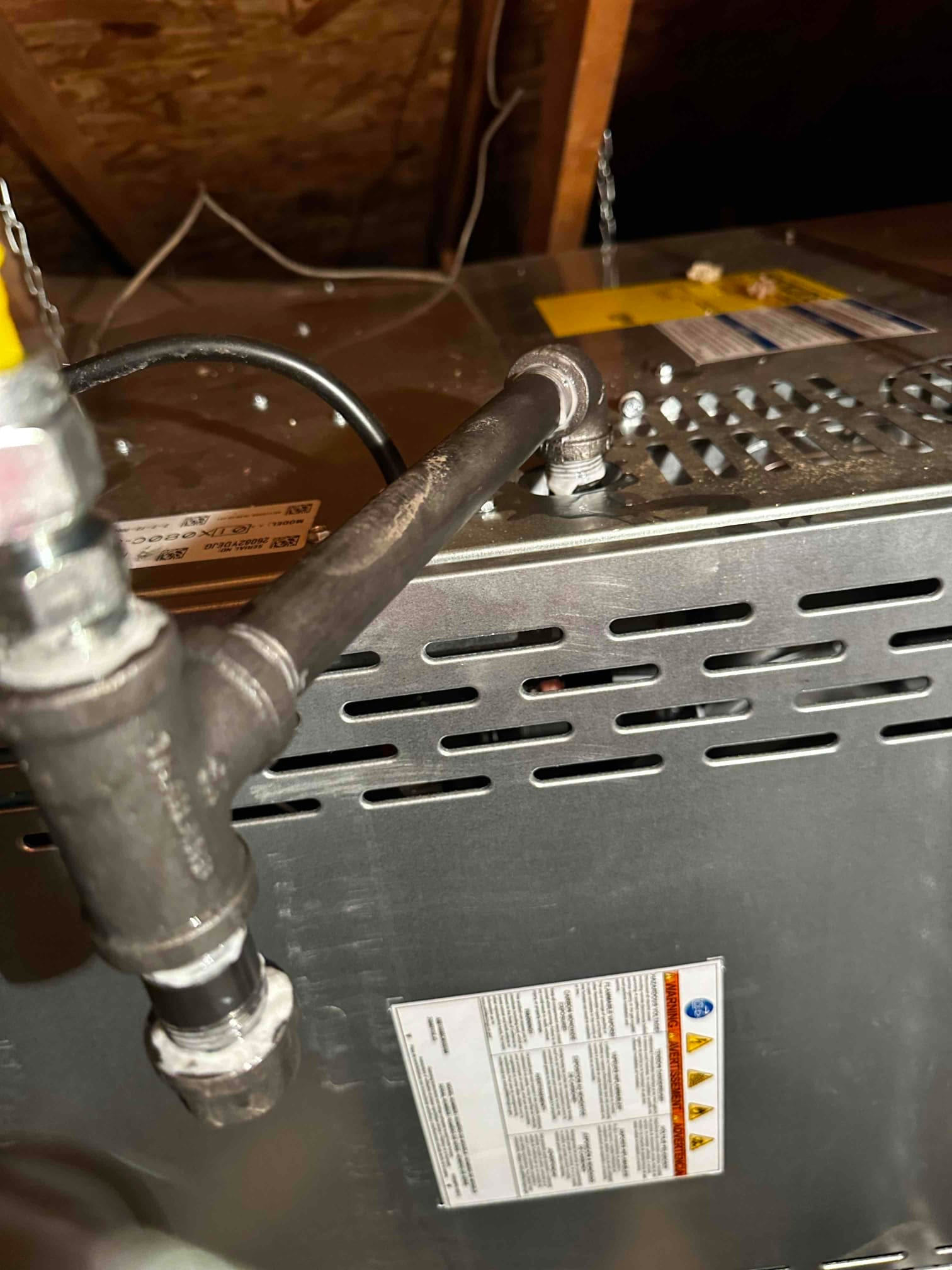 Rigid gas piping with union and drip leg connects to a suspended furnace in the attic, showing sealed threaded joints.