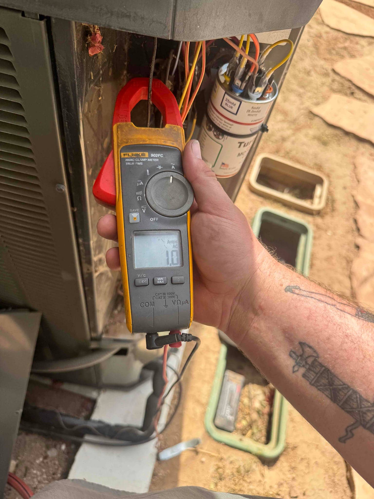 Clamp meter shows 10 A on a conductor at the outdoor condenser unit beside the run capacitor.
