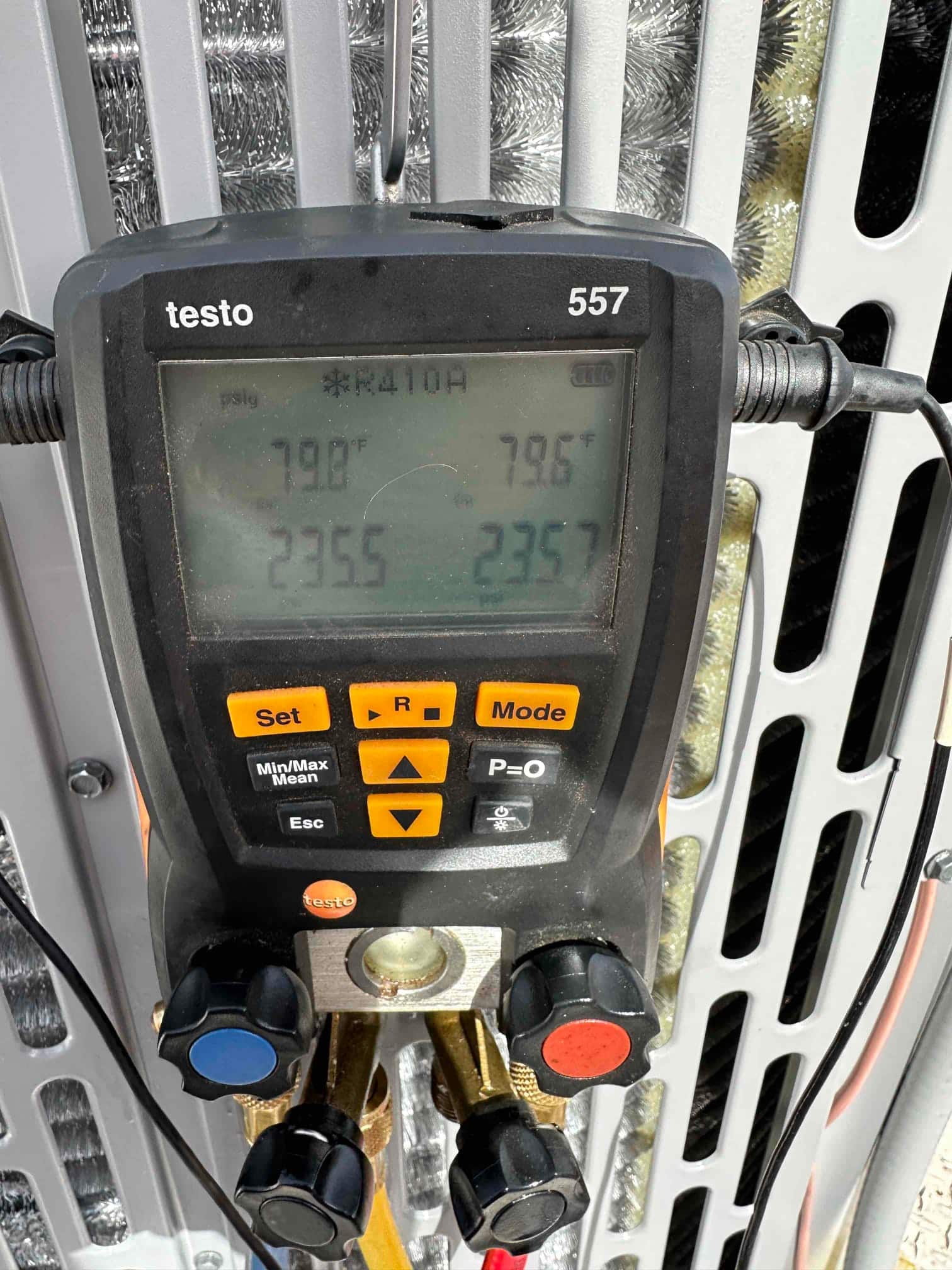 Digital manifold gauge set shows both sides holding equal high pressure during a nitrogen pressure test on the outdoor unit.