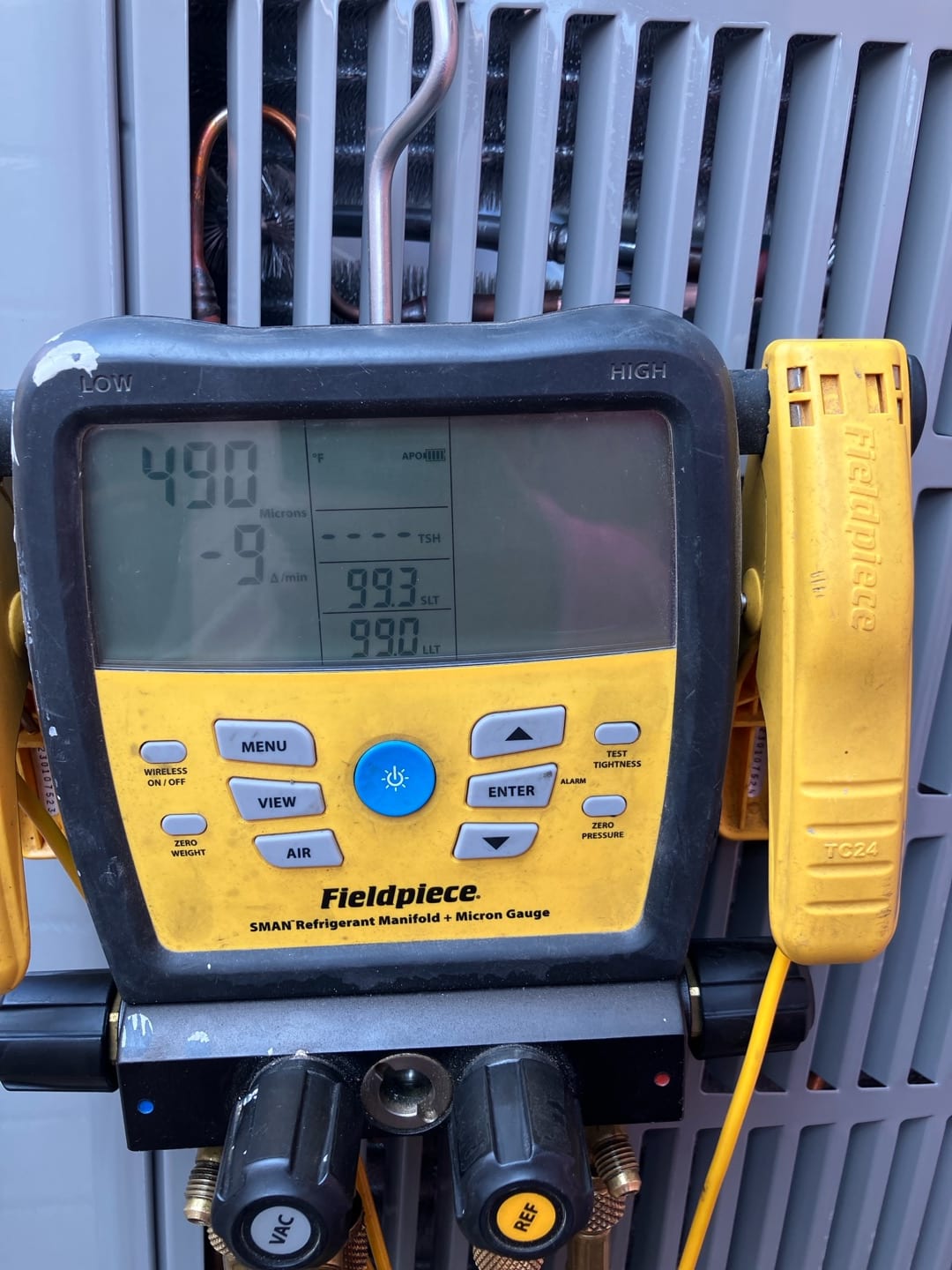 Digital micron gauge on the manifold displays 490 microns, documenting a deep vacuum during system evacuation.