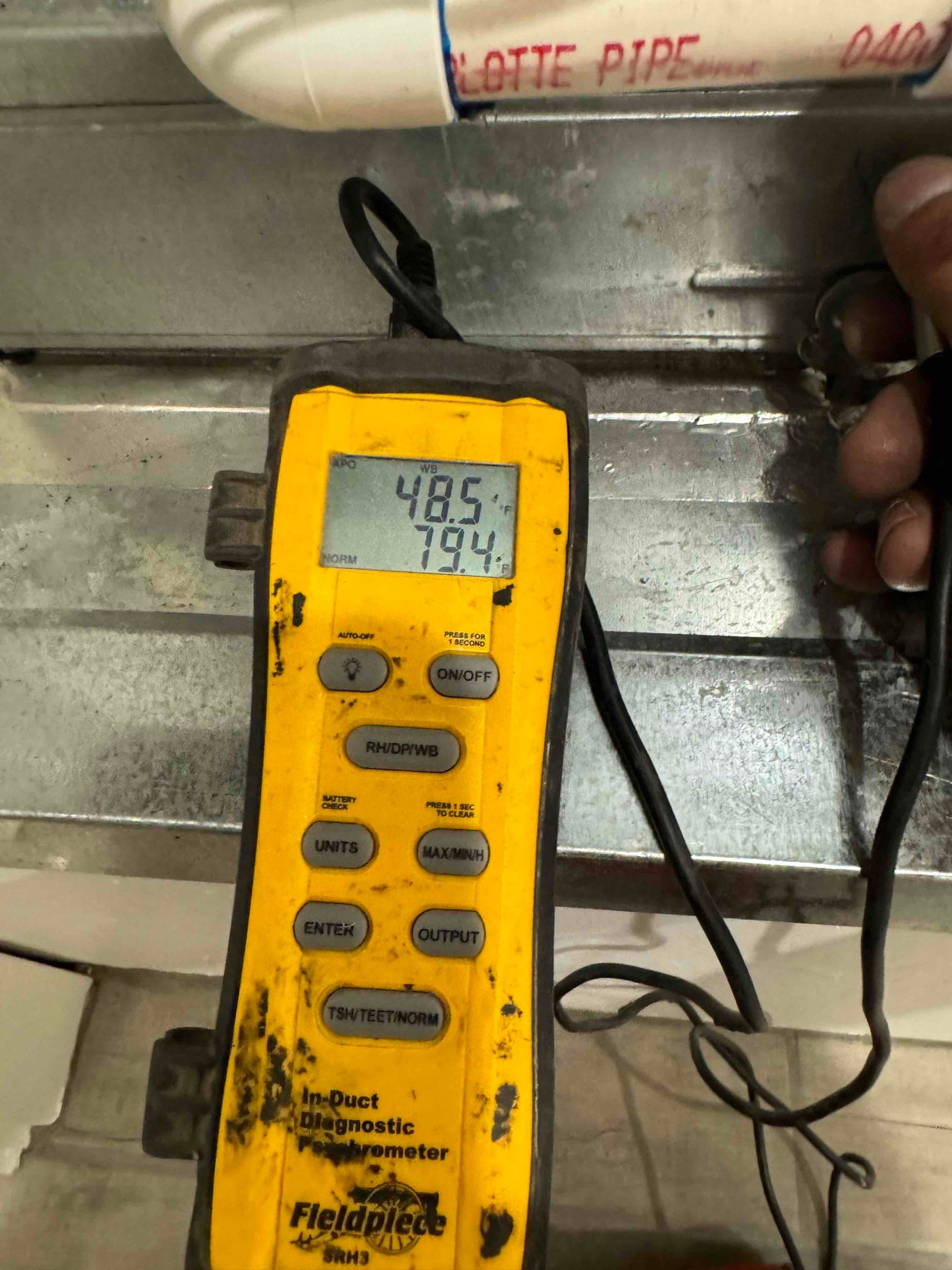 Digital thermometer placed at ductwork reads 48.5 degrees and 79.4 degrees during airflow temperature checks.