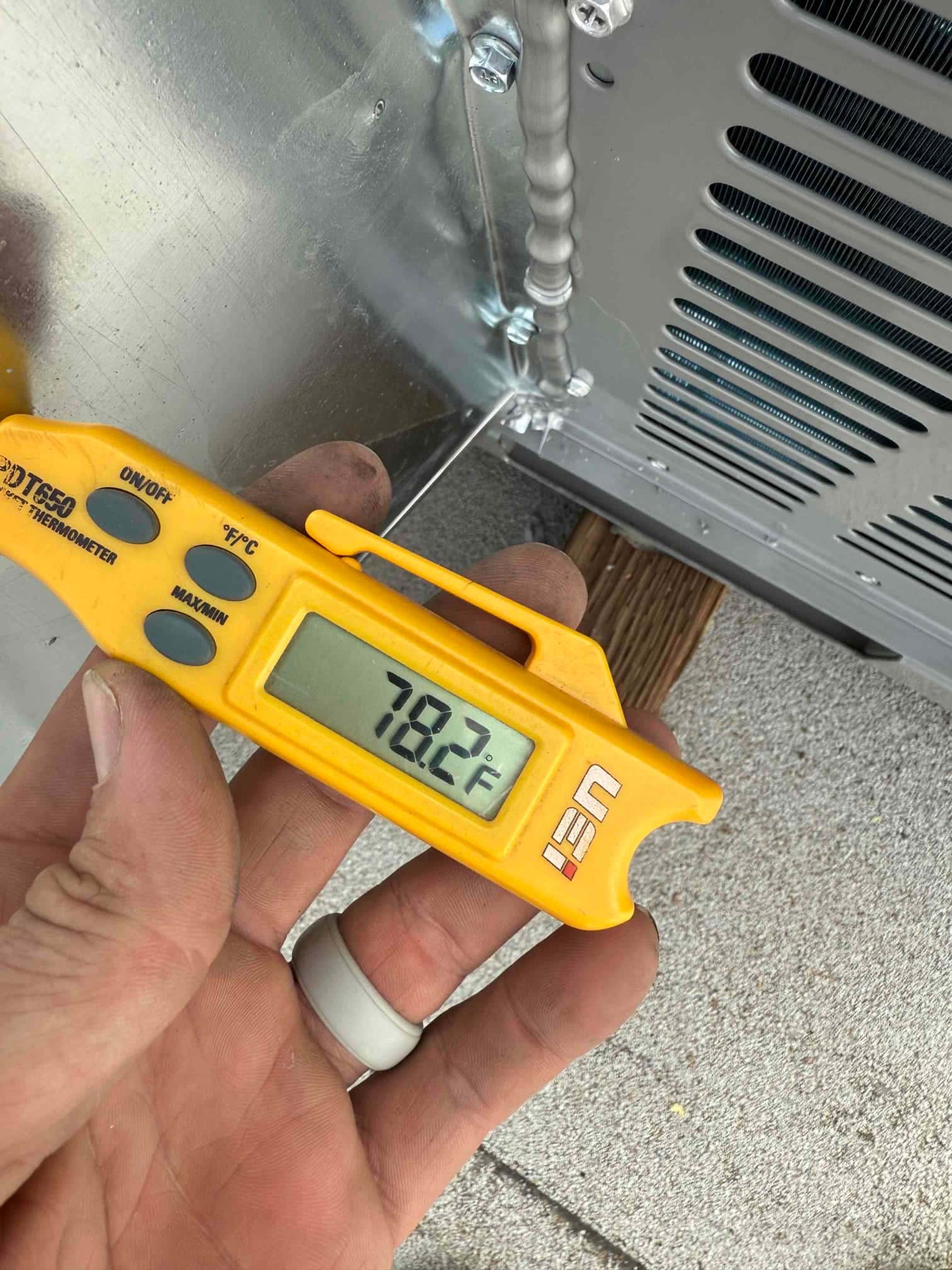 Digital thermometer shows 78.2°F at the HVAC unit, documenting a warm return-air temperature reading during commissioning.