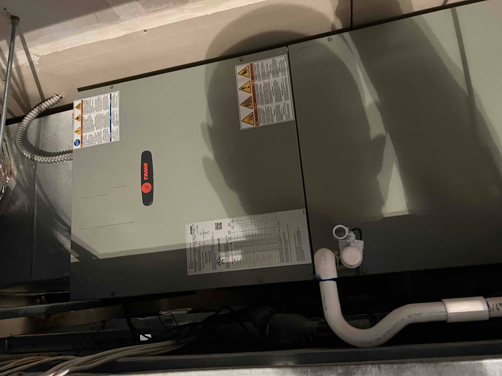 New air handler installed in attic with insulated condensate drain, electrical whip, and service panels secured.