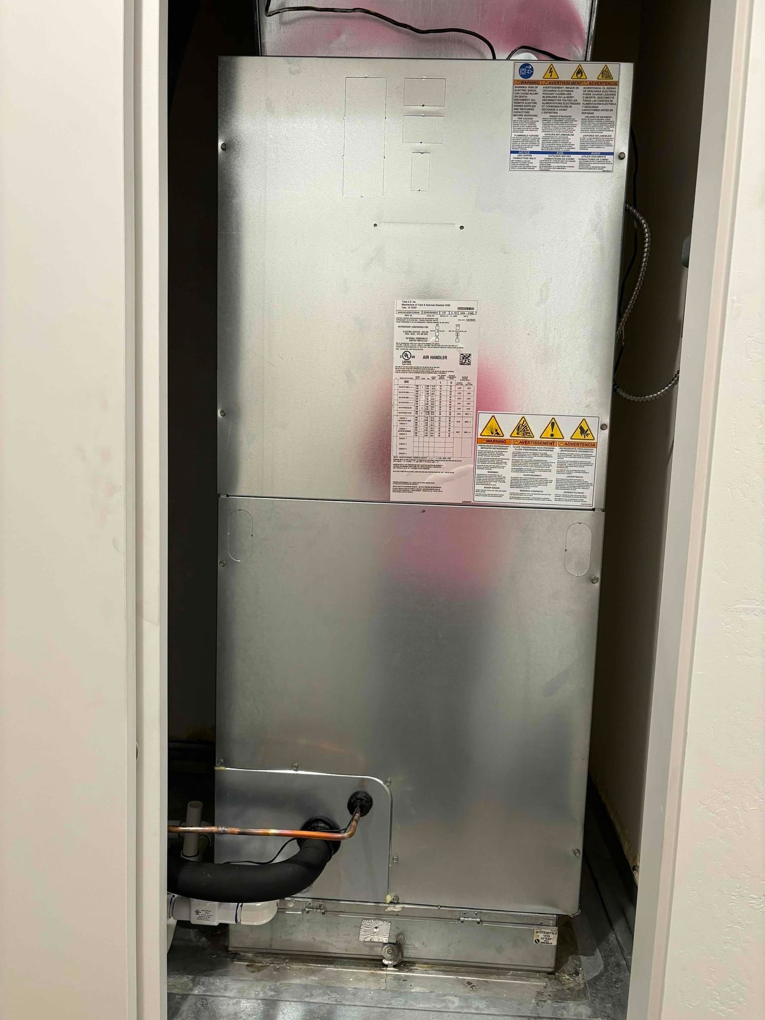 New air handler installed in closet with insulated suction line, copper liquid line, and condensate drain connected on a galvanized drain pan.