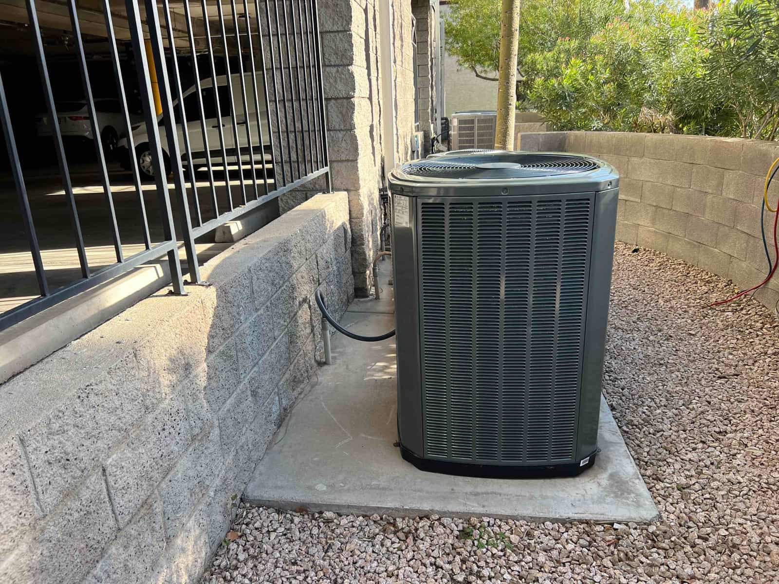 New outdoor condenser set on a level concrete pad with insulated line set routed along the wall in a clean service area.